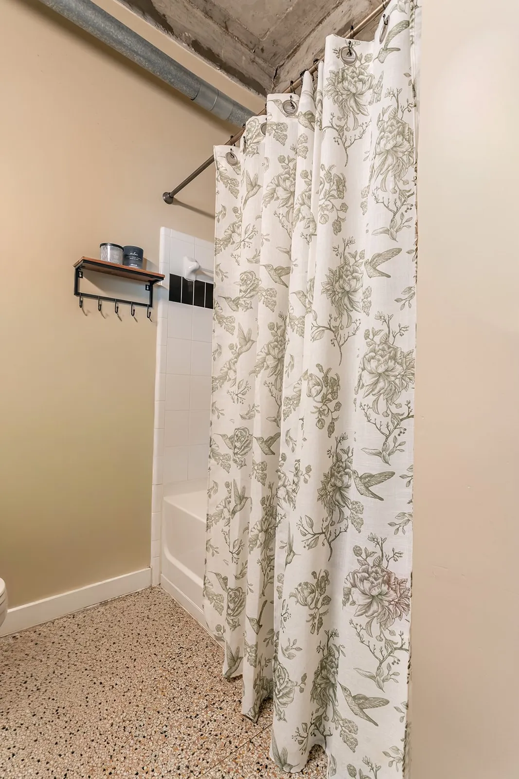 Bathroom featuring a white tub and tiled shower surround, complemented by a floral-patterned shower curtain
