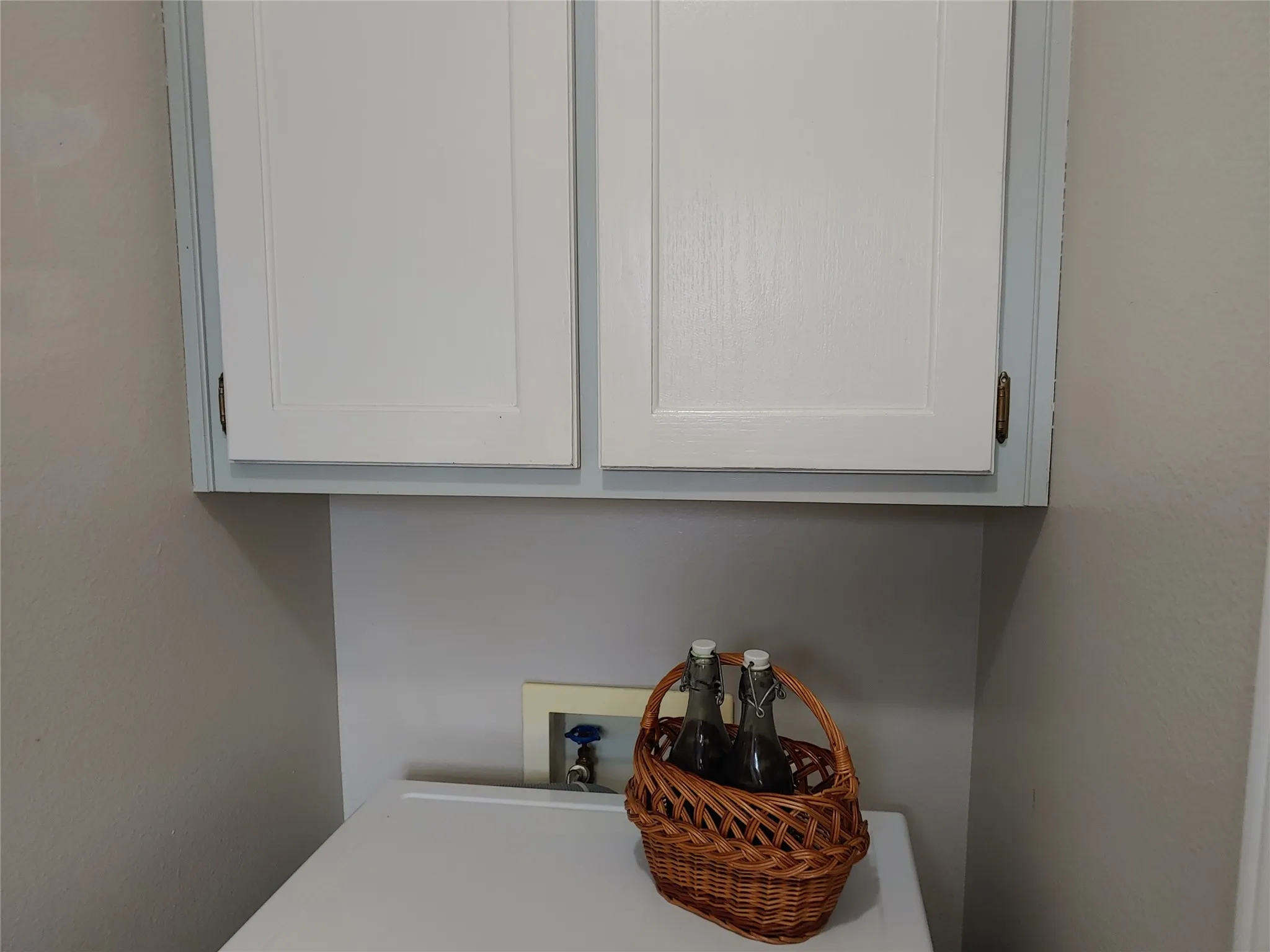 White upper cabinetry with recessed panel doors and brass-tone hardware
