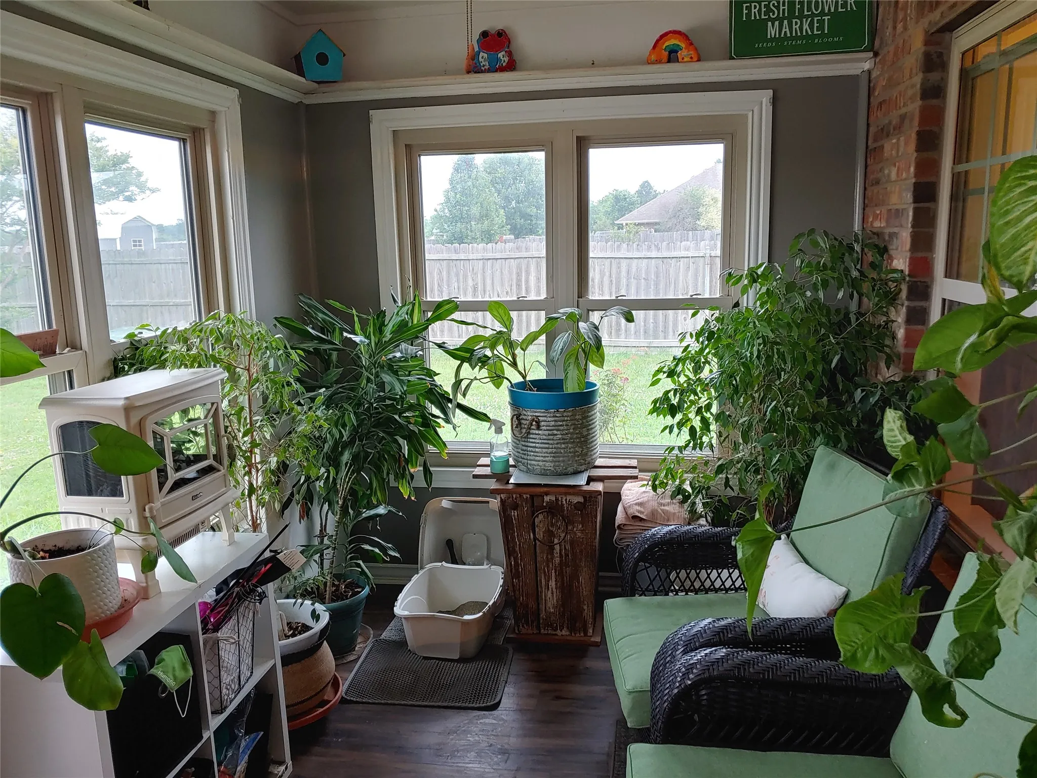 Sunroom with multiple windows, wood-finish flooring, and a brick accent wall