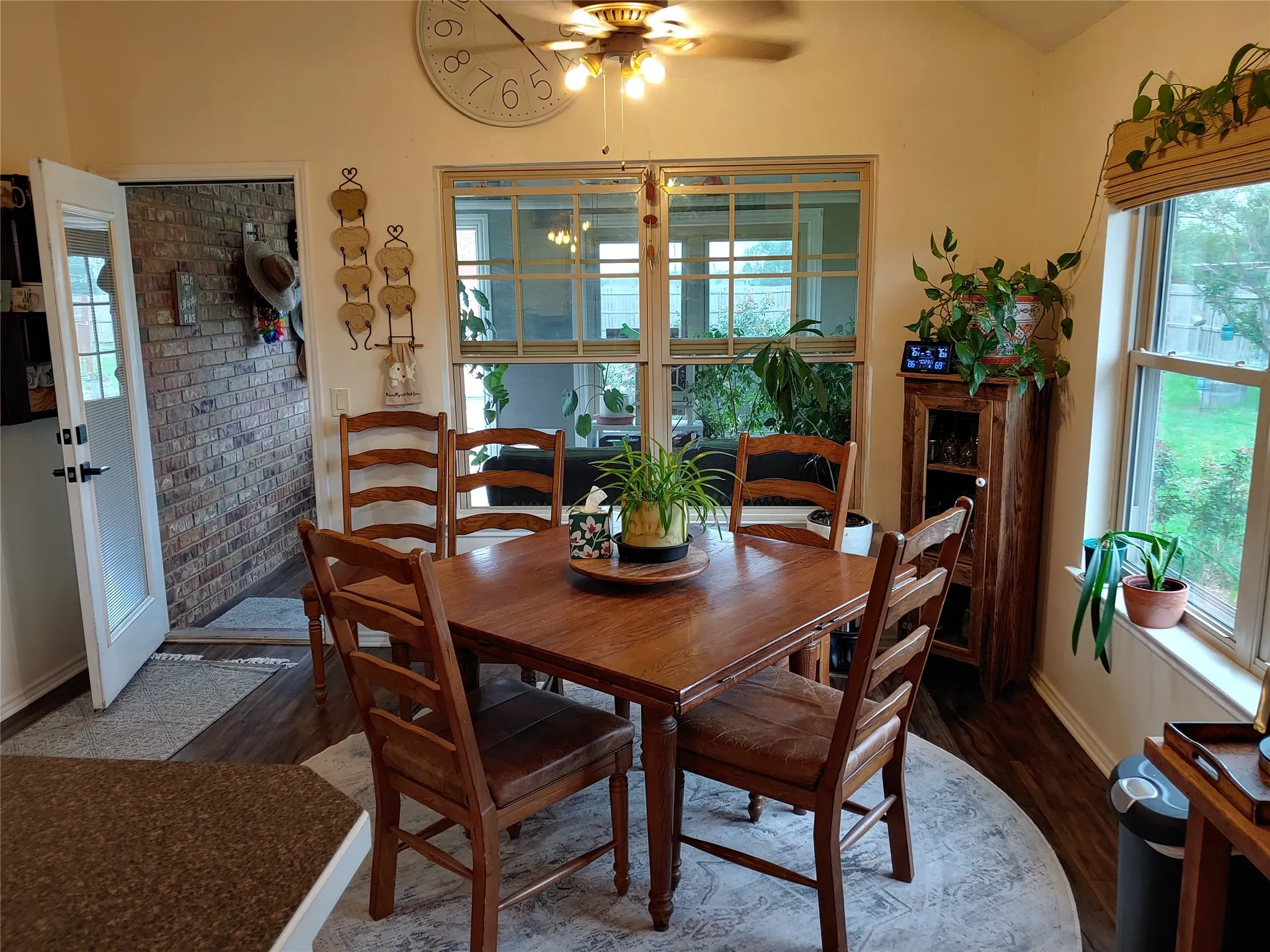 Dining area featuring wood-finish flooring, a large window overlooking the exterior, and a ceiling fan with integrated lighting