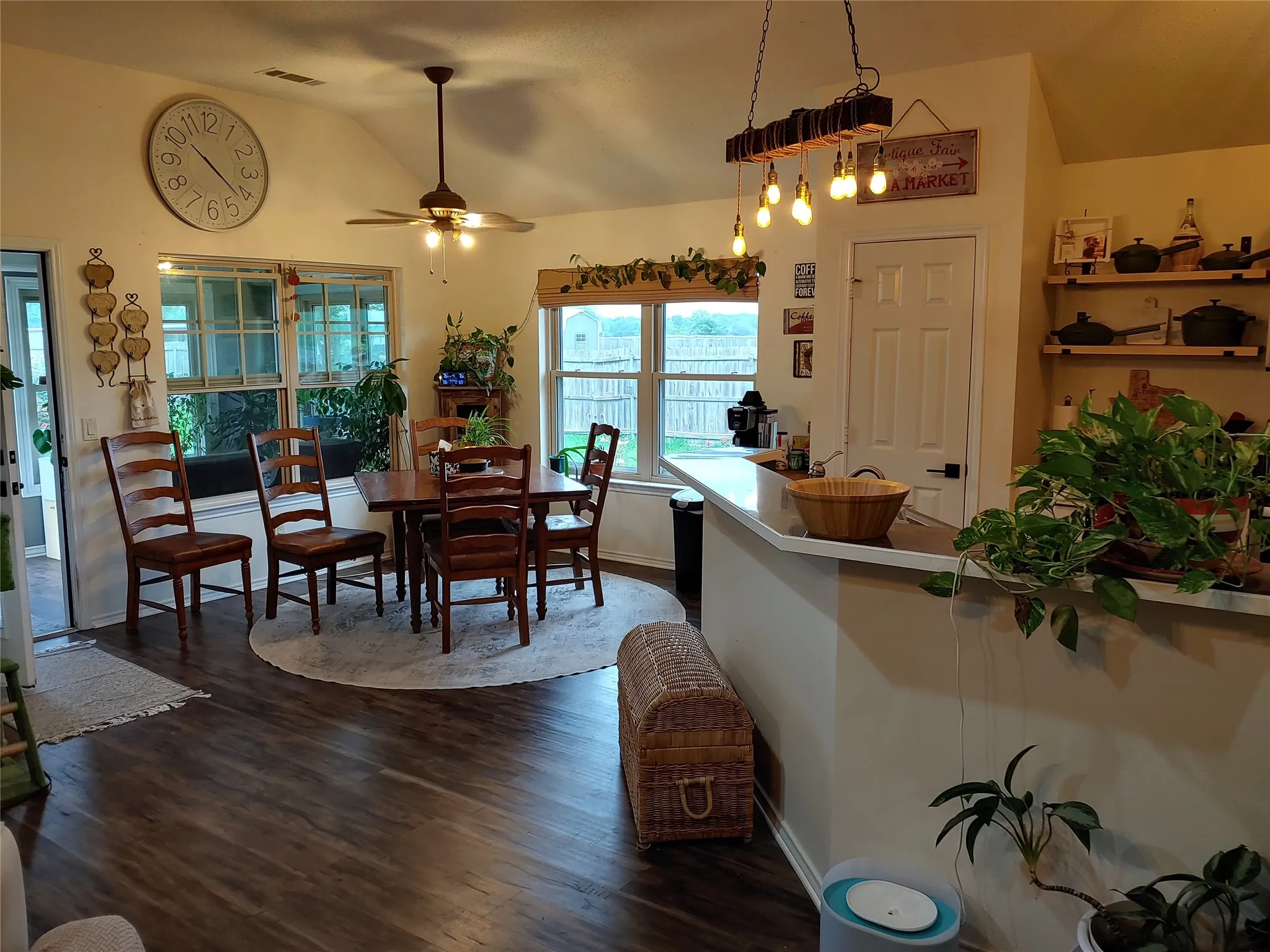 Vaulted ceiling dining area featuring wood-finish flooring, a ceiling fan with light, and multiple windows