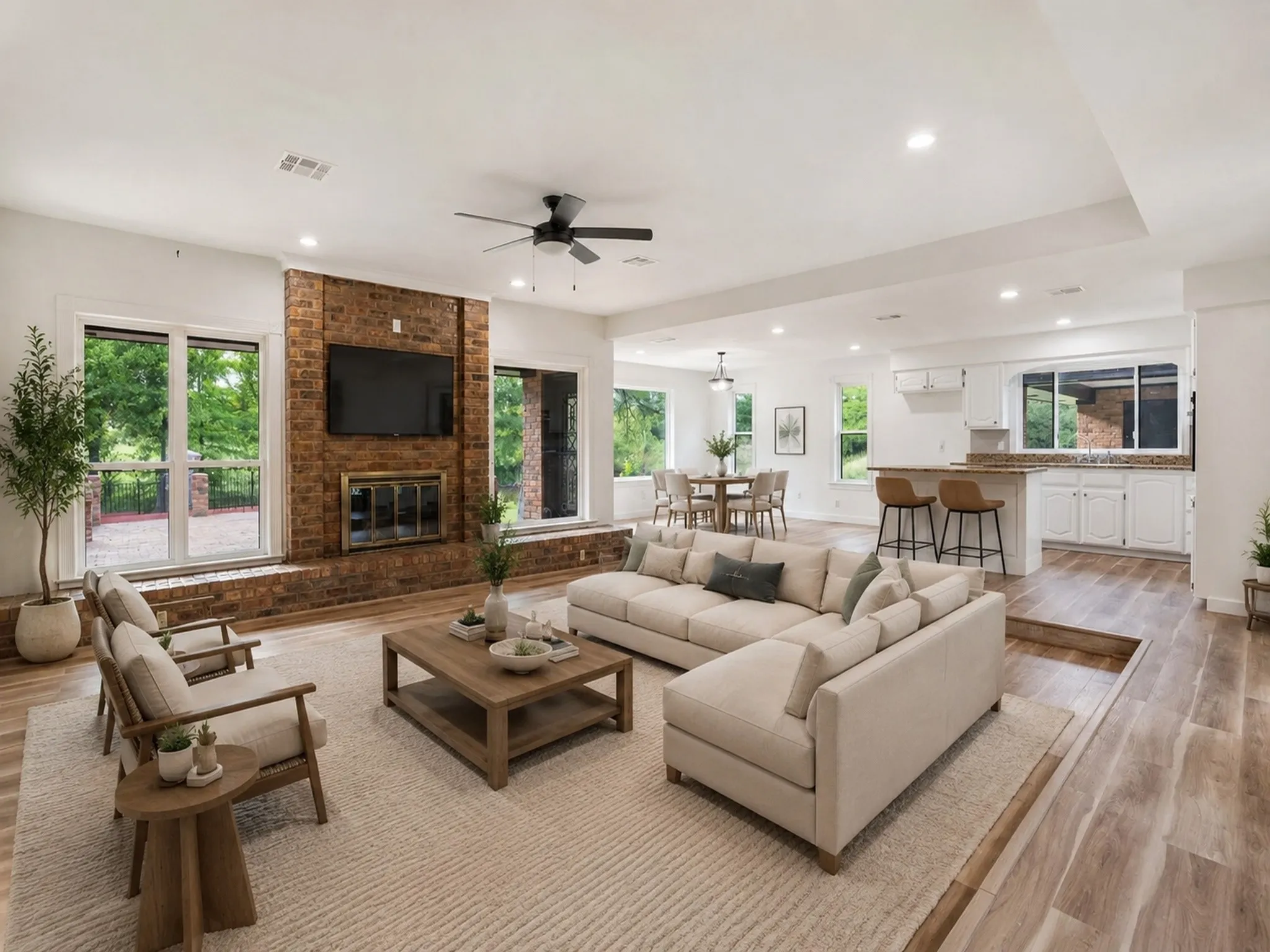 Virtually Staged photo.  Spacious open-concept living area featuring wood-finish flooring, a brick fireplace