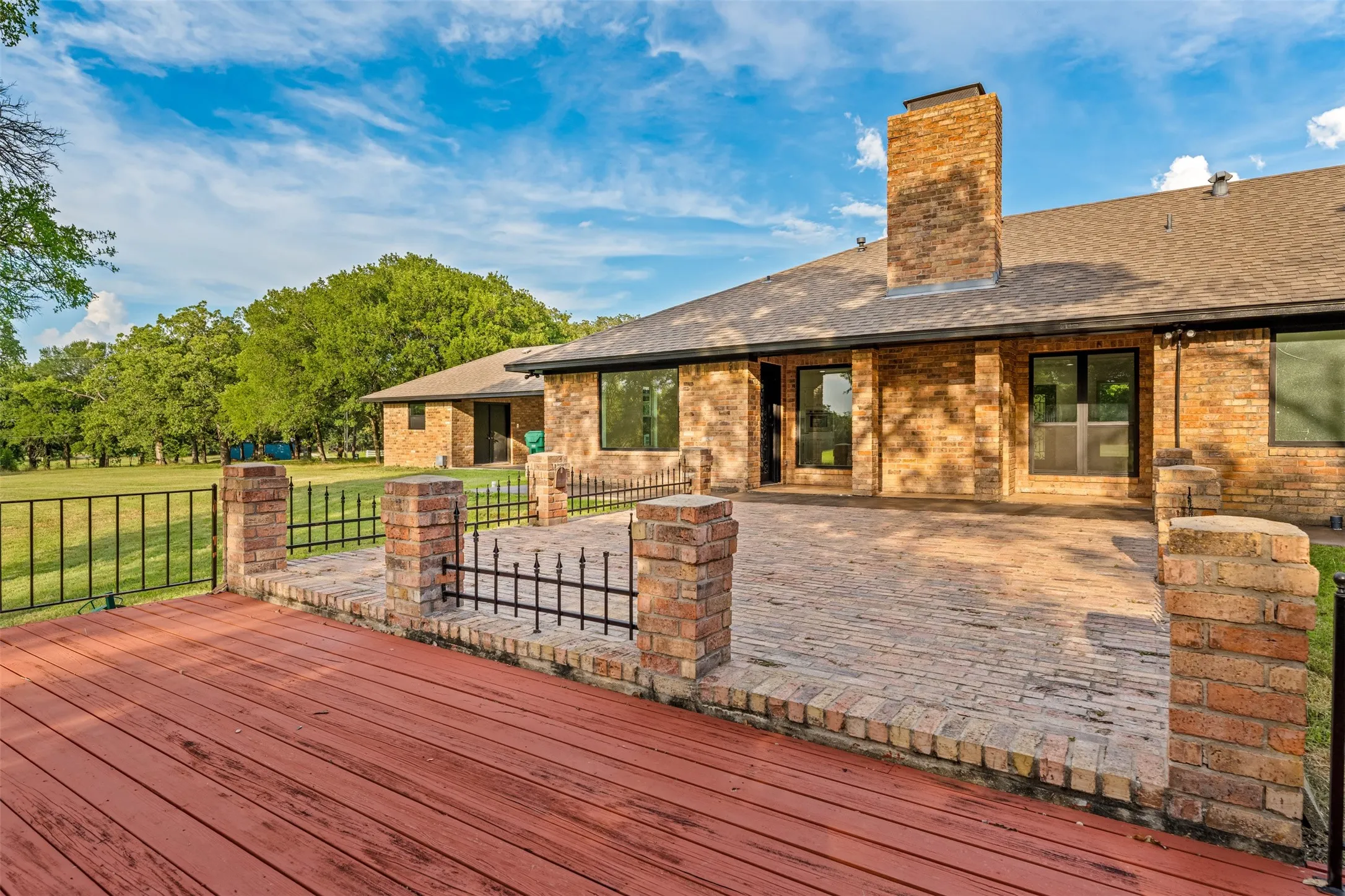Multi-level outdoor living area featuring a wood-finish deck and brick paver patio