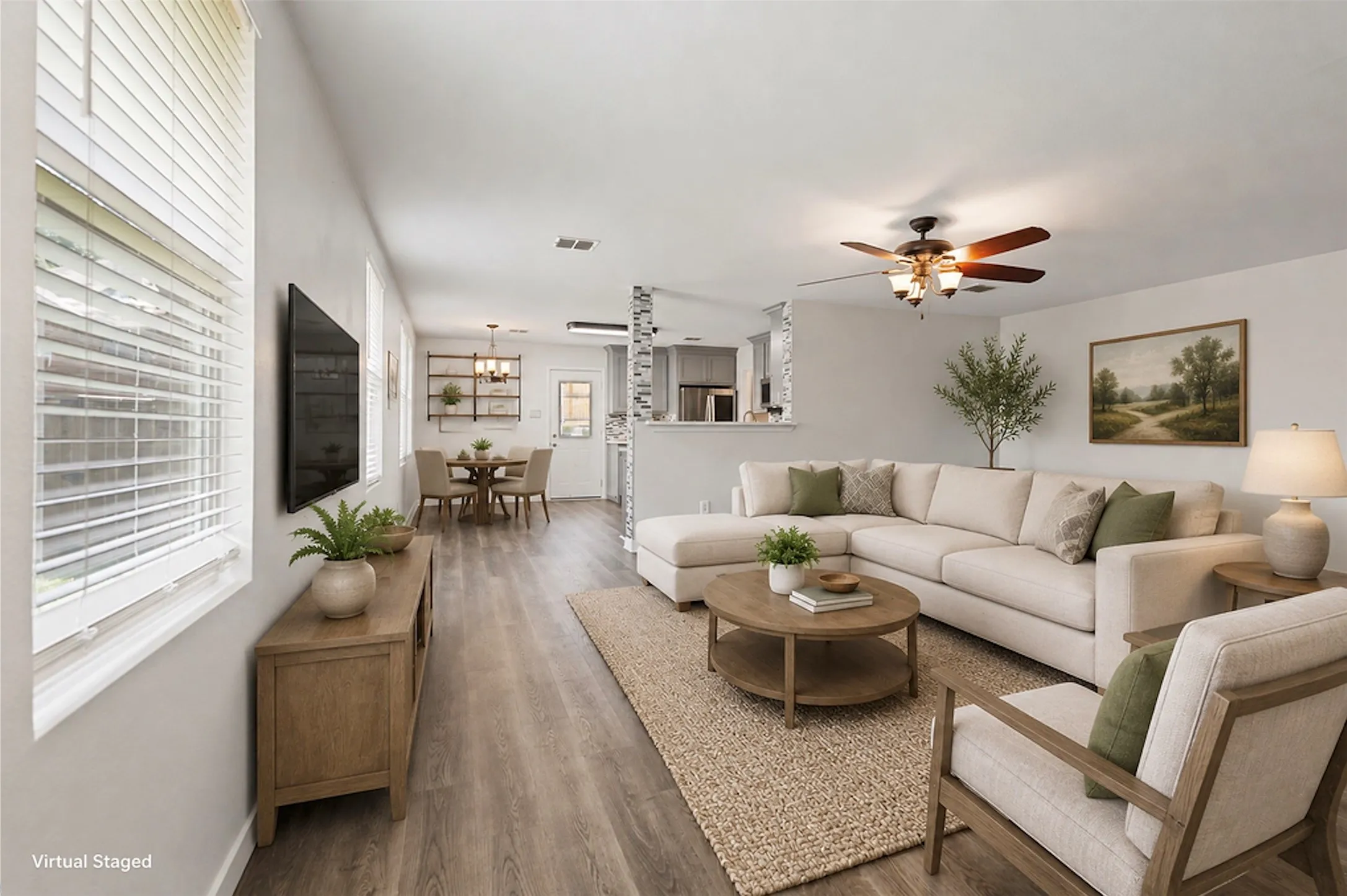 Spacious living area featuring wood-finish flooring, multiple windows with blinds, and a ceiling fan with integrated lighting