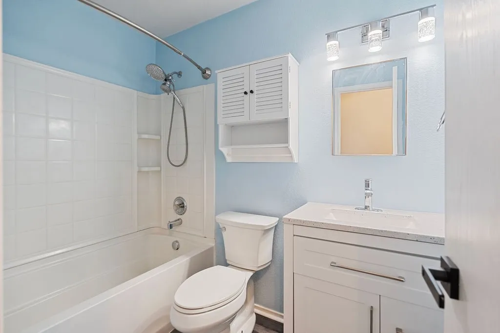 Bathroom featuring a white bathtub, ceramic tile surround, built-in shelving, and a vanity with a white countertop and integrated sink