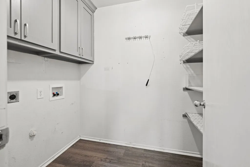 Dedicated utility space featuring wood-finish flooring, upper cabinetry with brushed nickel hardware, and wall hook storage