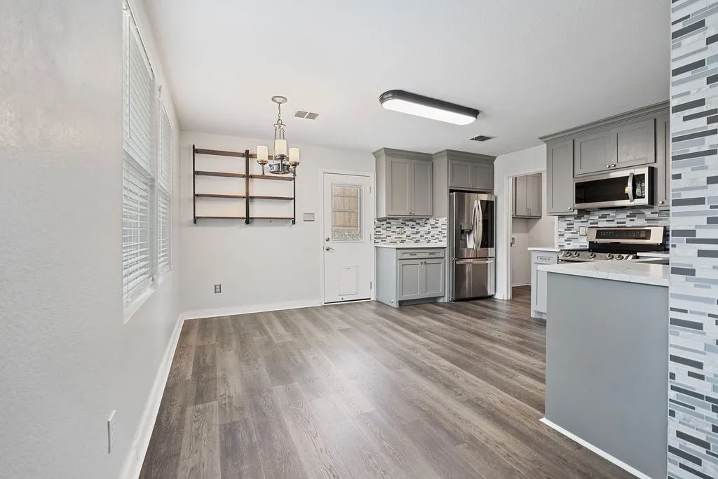 Open-concept kitchen and dining area featuring wood-finish flooring, recessed lighting, and a modern chandelier