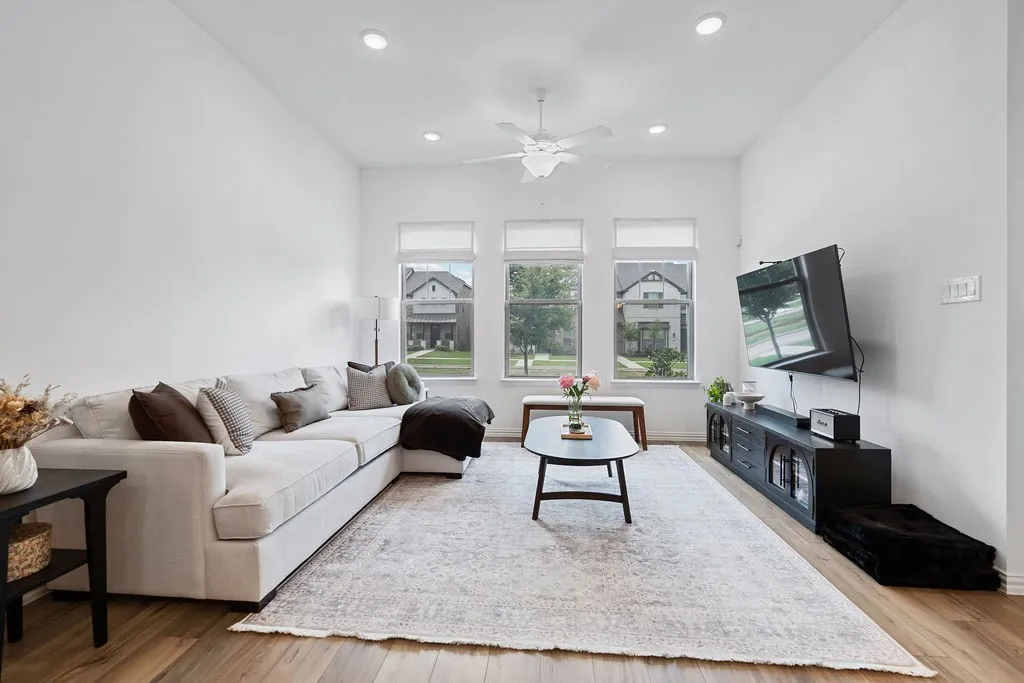 Spacious living area featuring wood-finish flooring, recessed lighting, and a ceiling fan