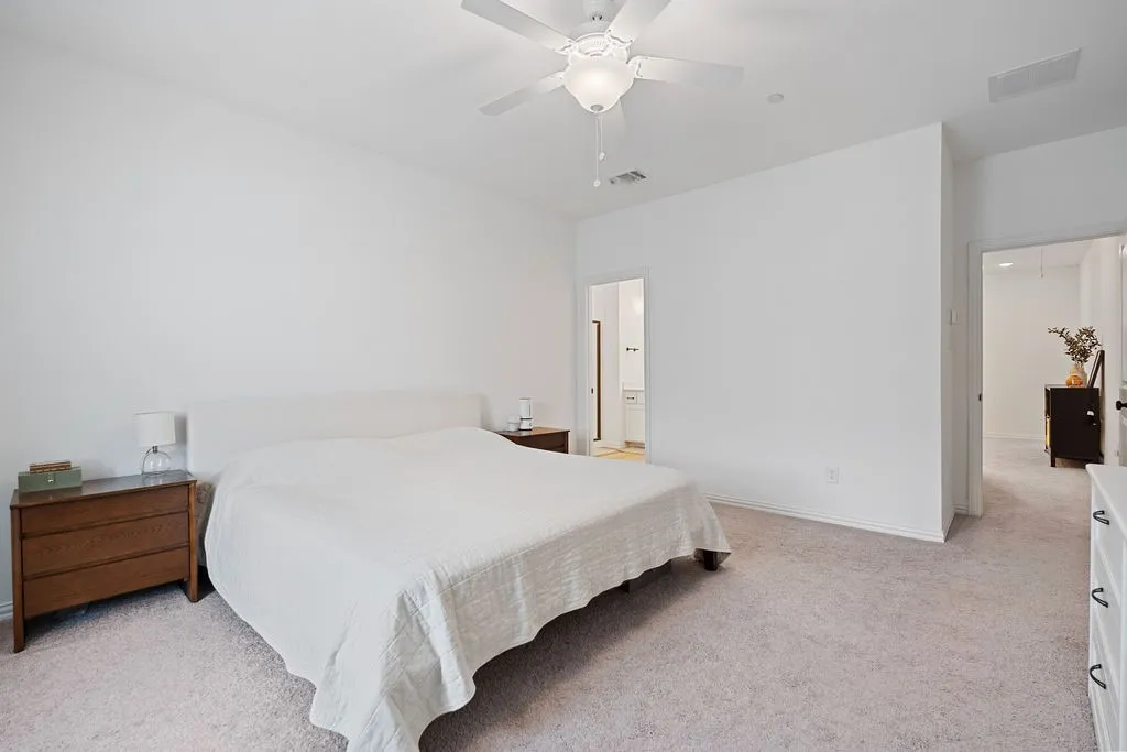 Carpeted room with a ceiling fan light fixture and neutral-toned walls