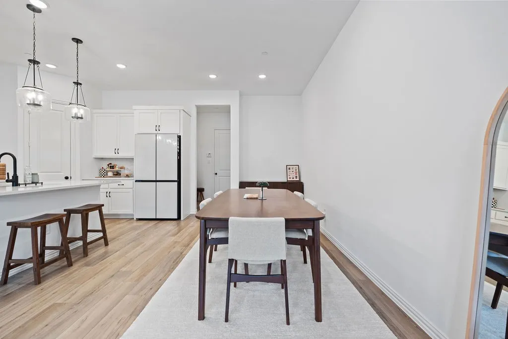 Open-concept living space with light wood-finish flooring, recessed lighting, white perimeter cabinetry, and an island with pendant lighting