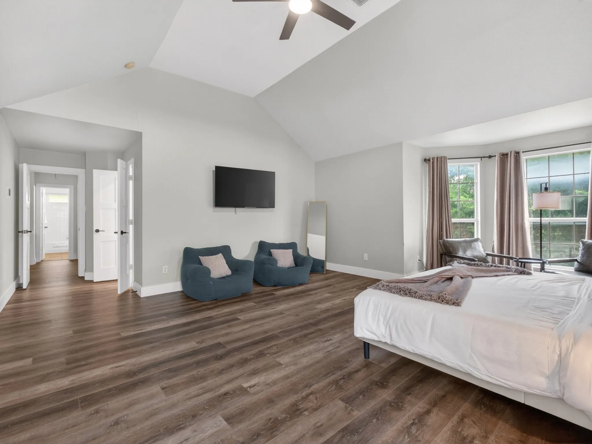 Spacious room featuring vaulted ceilings, wood-finish flooring, and multiple windows
