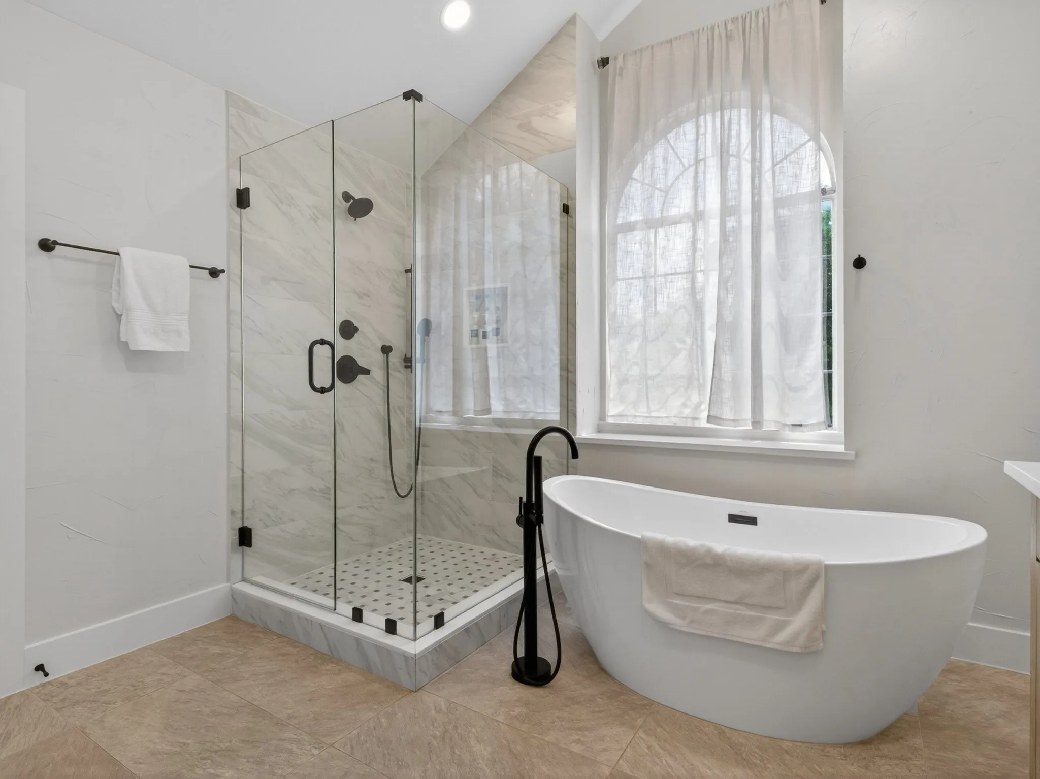 Freestanding soaking tub with a floor-mounted matte black faucet