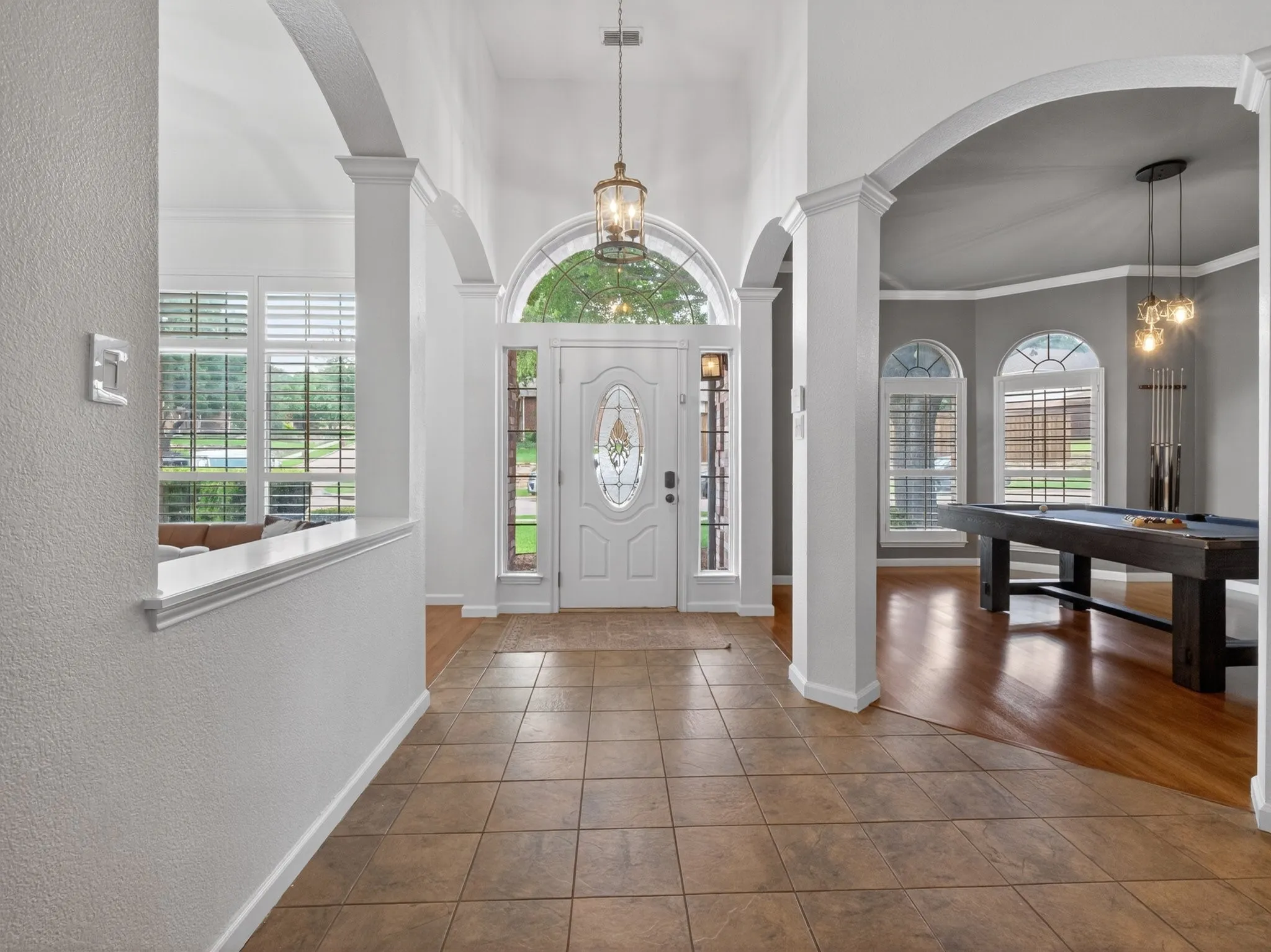 Foyer featuring a decorative glass-paneled entry door, arched transom window, and tile flooring