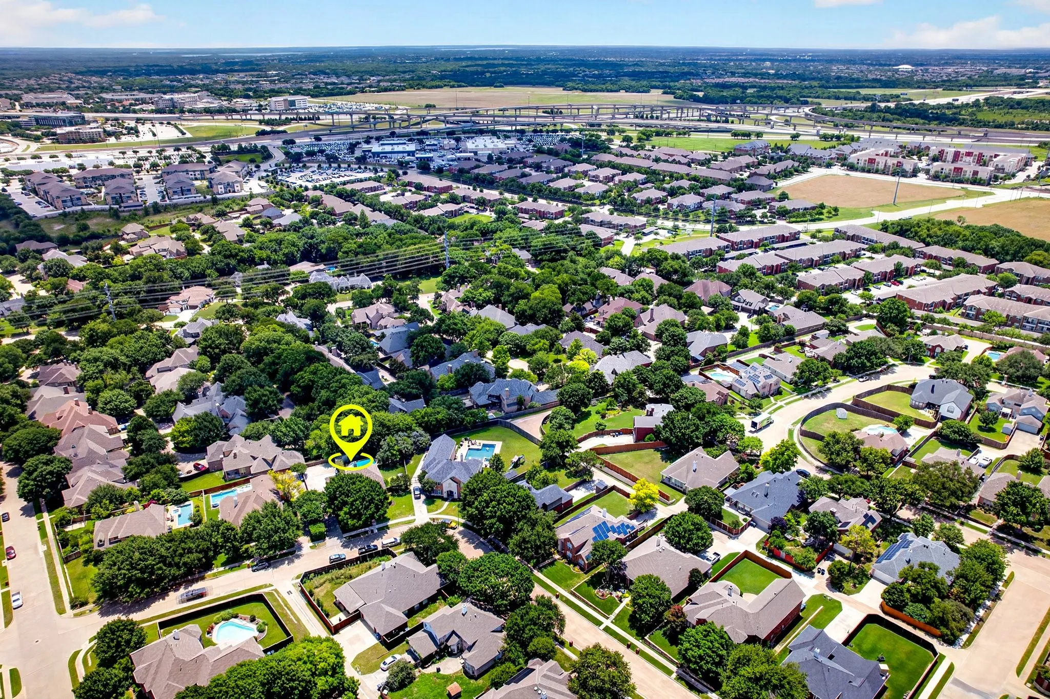 Aerial perspective showcasing a residential neighborhood with a mix of single-family homes and mature tree coverage