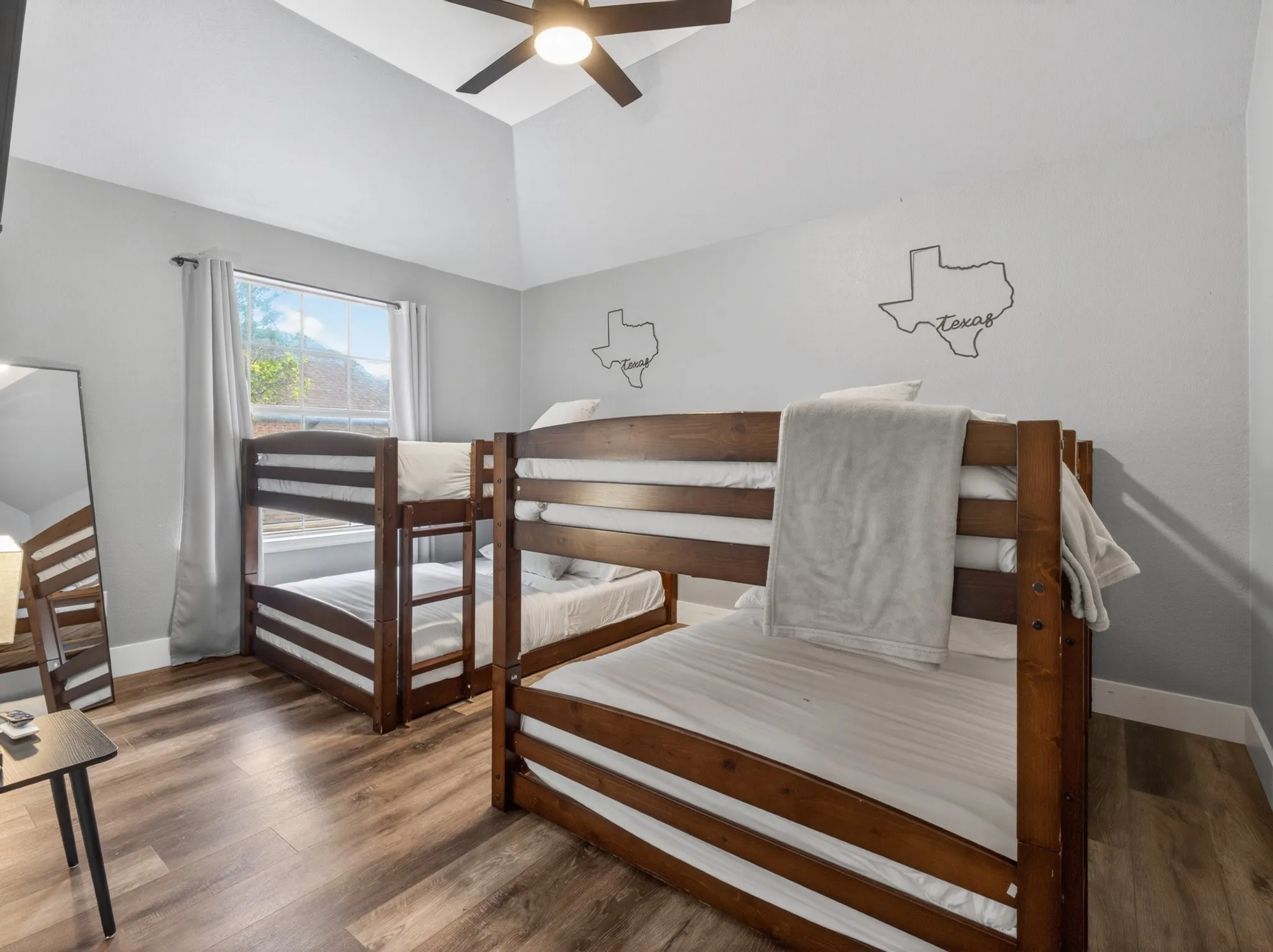 Vaulted ceiling room with wood-finish flooring, a window with exterior views, and a ceiling fan