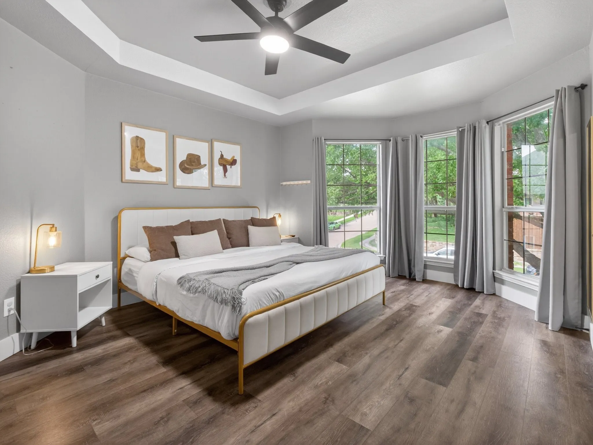 Bedroom featuring wood-finish flooring, a tray ceiling, and a ceiling fan with integrated lighting