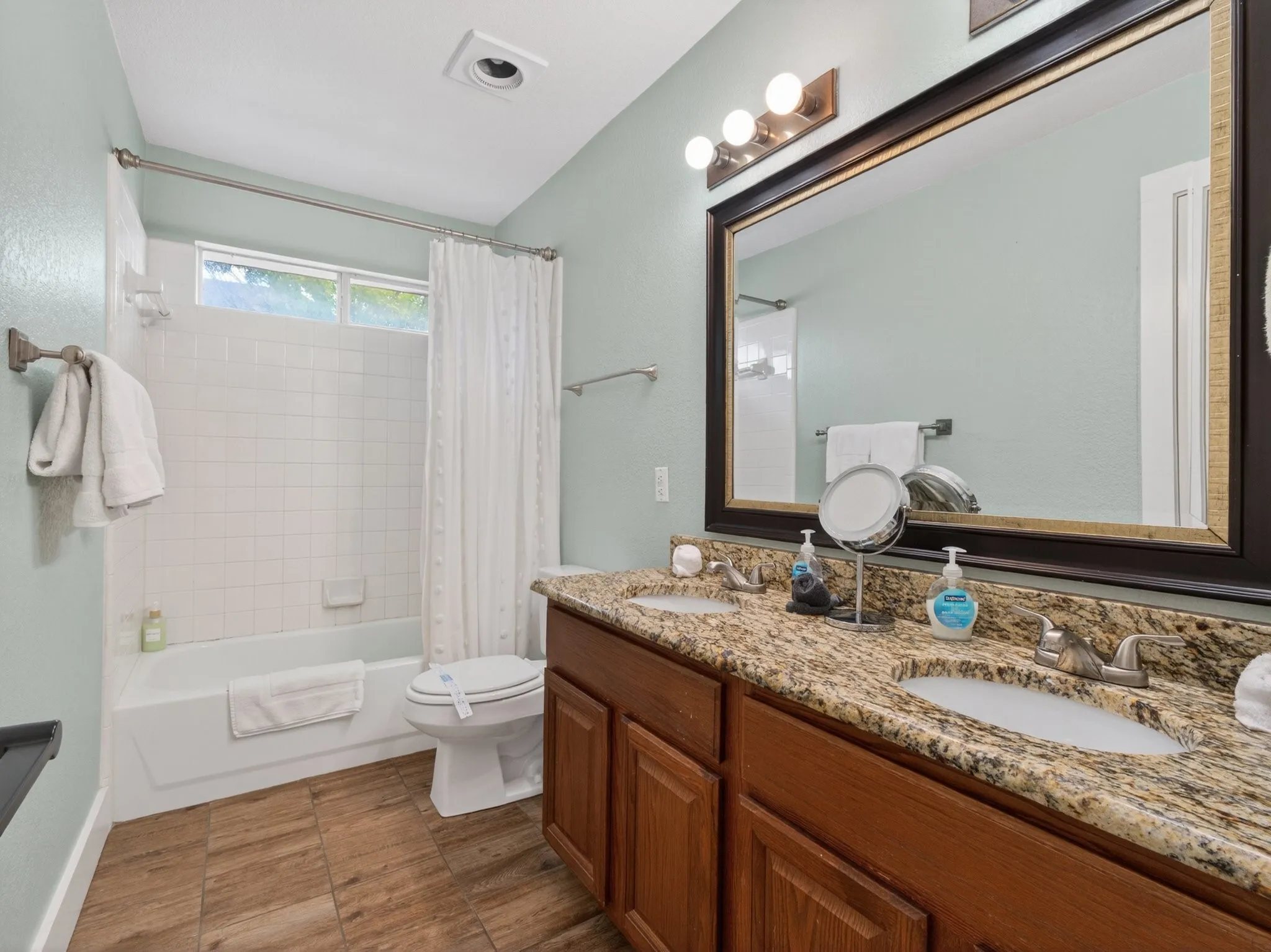 Bathroom featuring a double vanity with granite countertops, wood-finish cabinetry, and dual undermount sinks