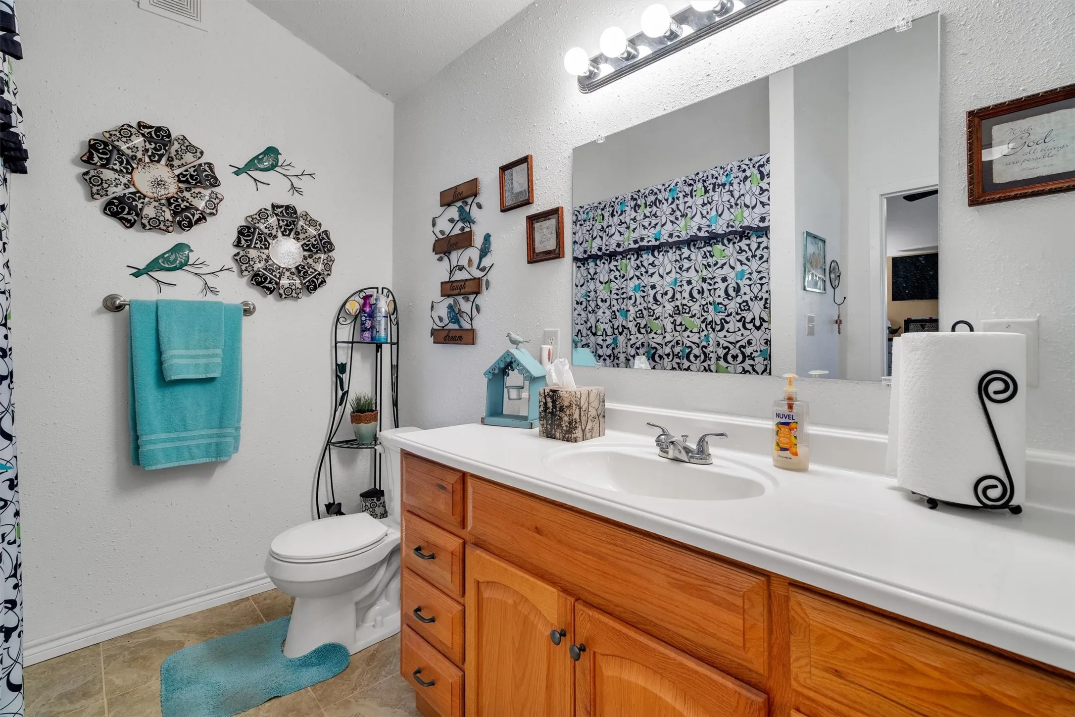 Bathroom featuring a single vanity with a white countertop and natural wood-finish cabinetry