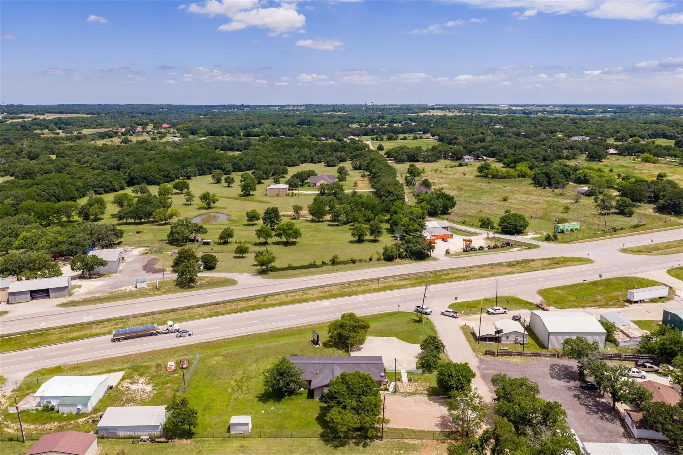 Expansive rural landscape featuring a highway, scattered trees, and several structures