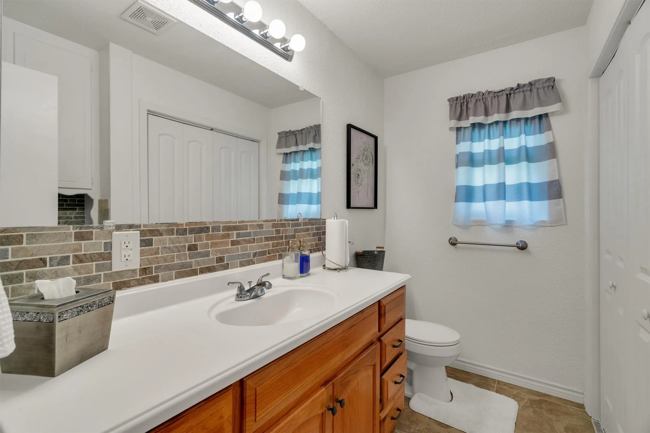 Bathroom vanity with a white countertop and integrated sink, a rectangular mirror, and a tile backsplash