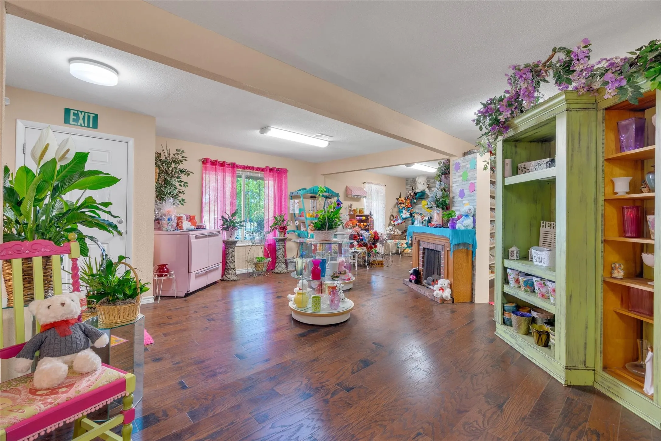 Expansive room featuring dark wood-finish flooring, recessed lighting, and a prominent green built-in shelving unit