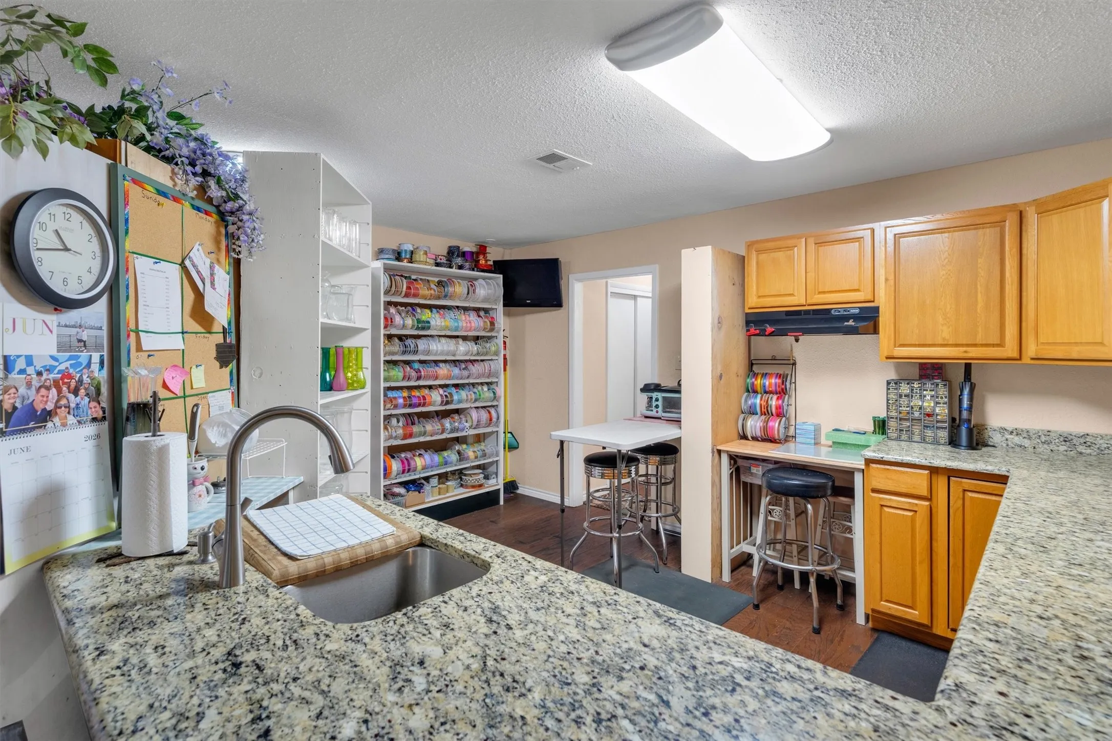 Granite-look countertops with an undermount sink and a gooseneck faucet complement the wood-finish cabinetry