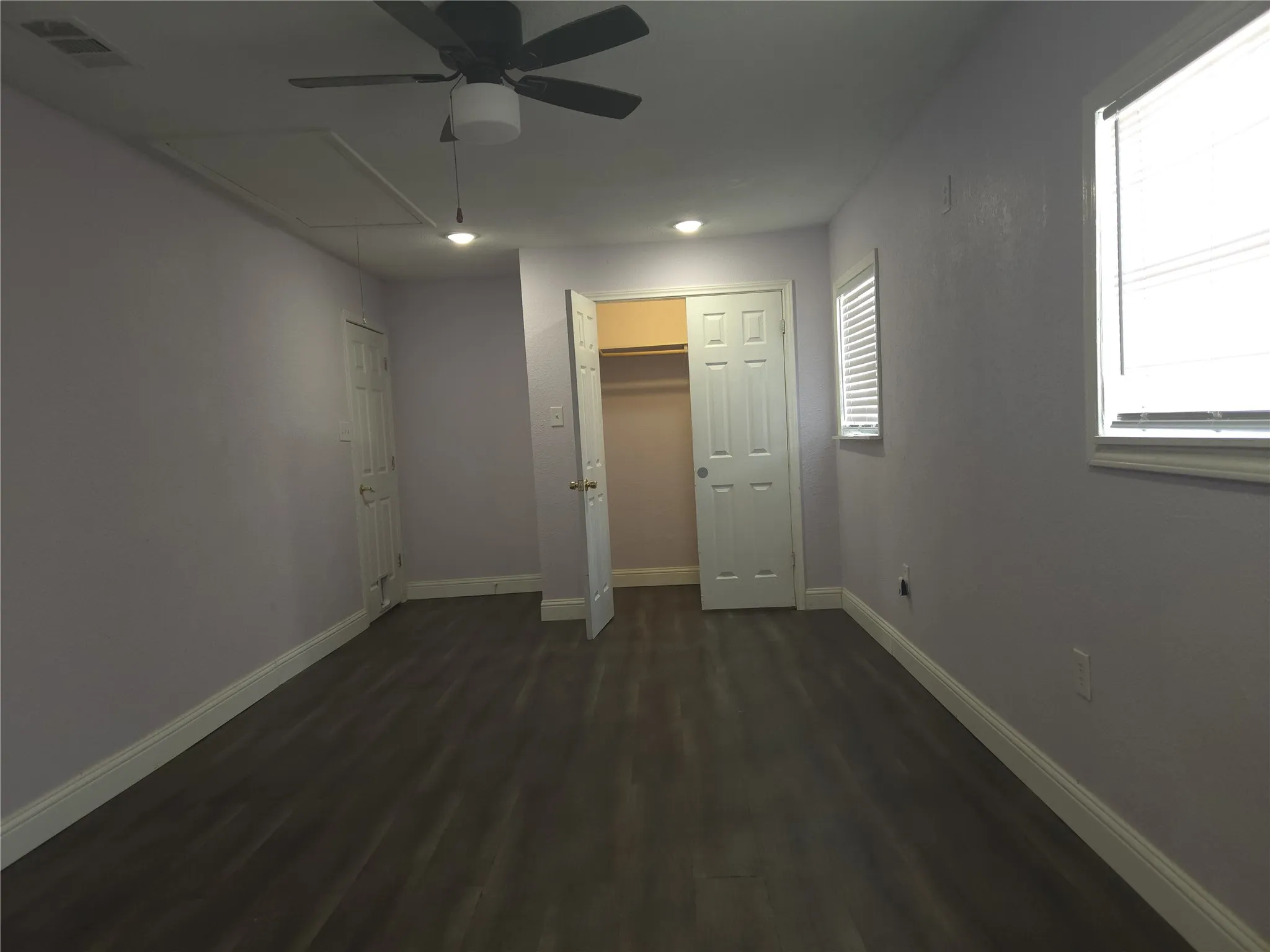Spacious room featuring wood-finish flooring, a ceiling fan, recessed lighting, and ample natural light through multiple windows