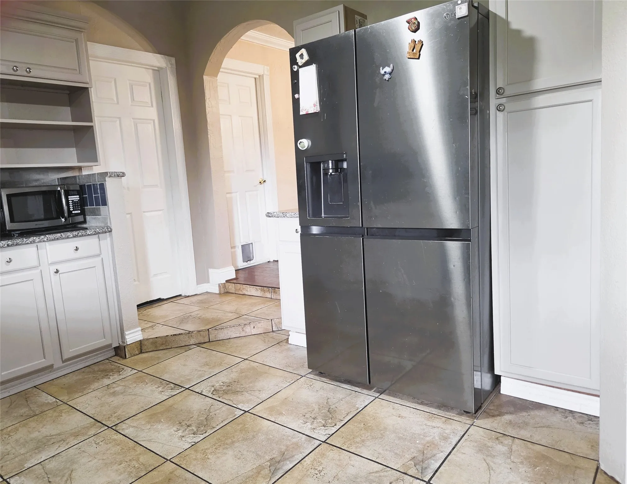 Kitchen featuring light-toned tile flooring, white cabinetry, and stone-finish countertops