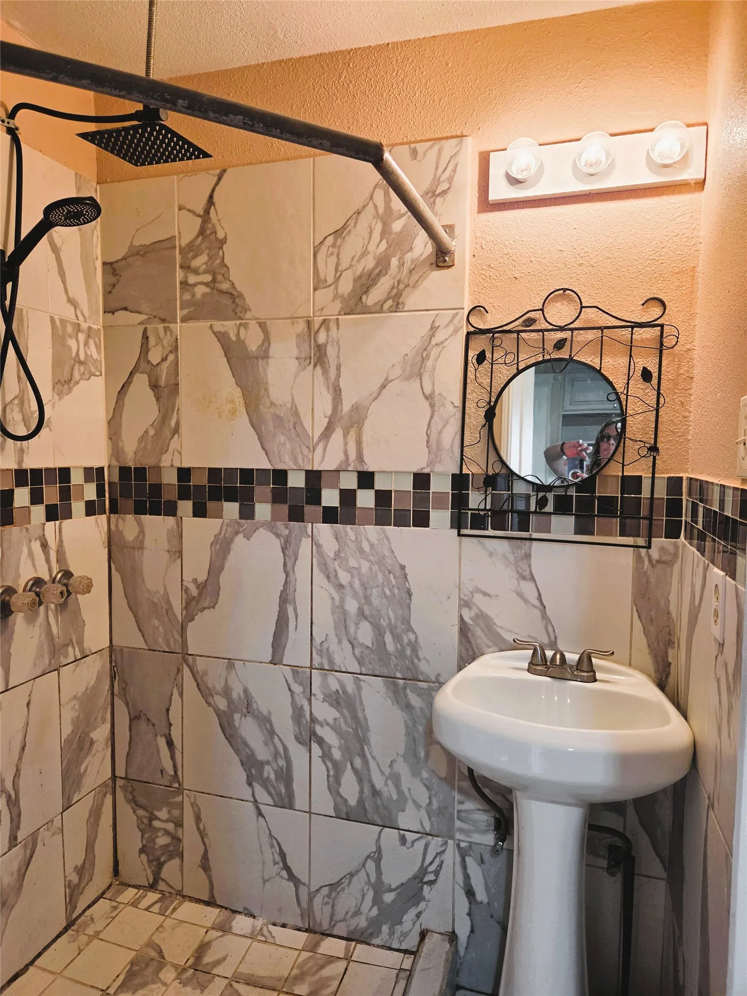 Pedestal sink with a tile backsplash featuring a mosaic accent band