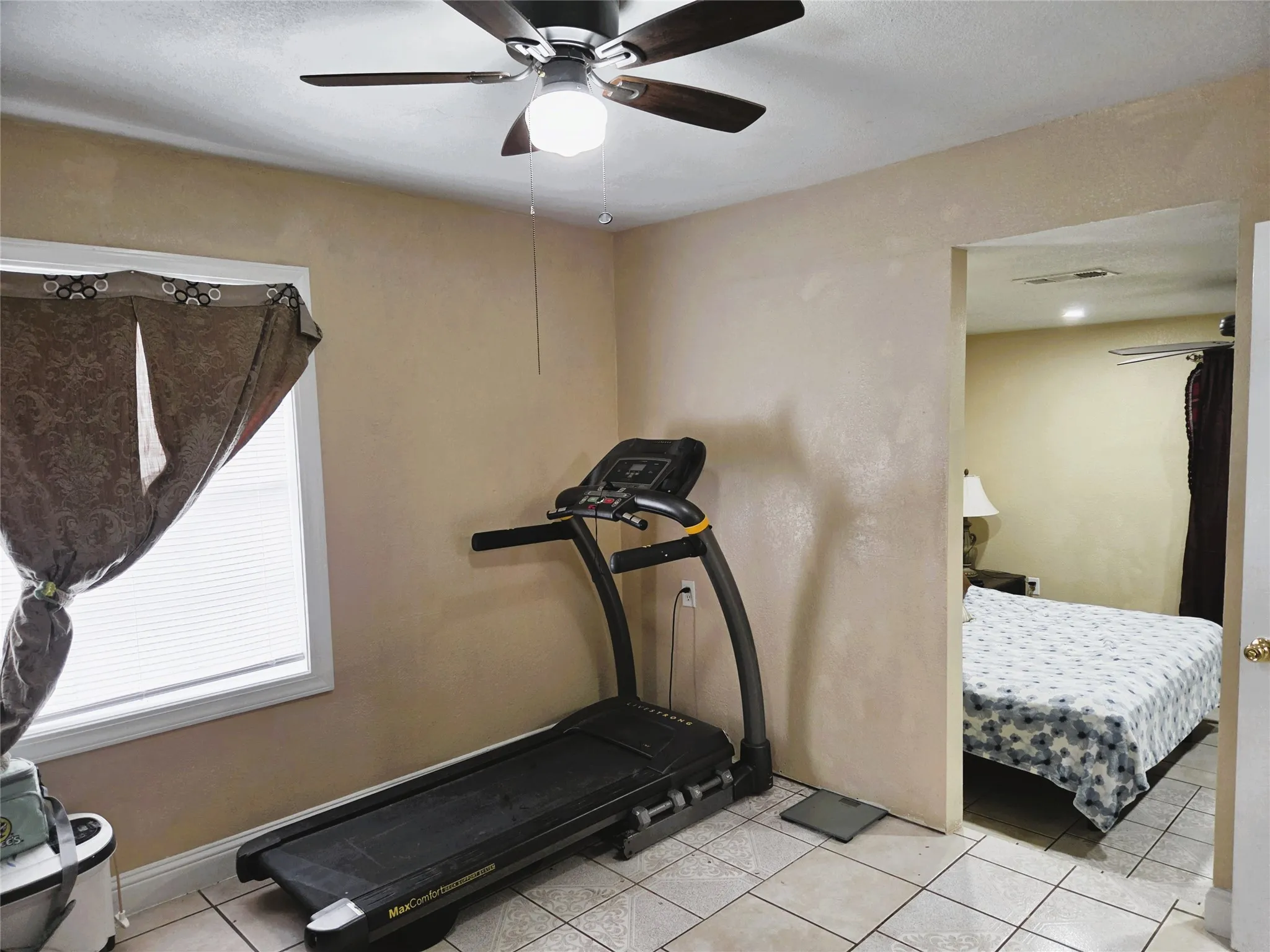 Room featuring tile flooring, a ceiling fan with light fixture, and a window with blinds