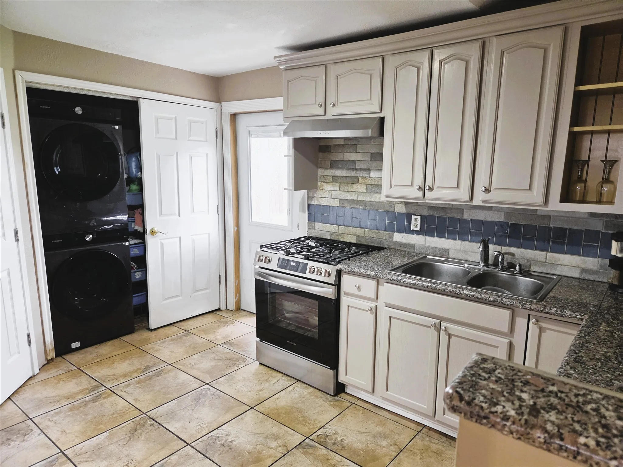 Kitchen featuring light-toned cabinetry, granite-finish countertops, and a stainless steel gas range