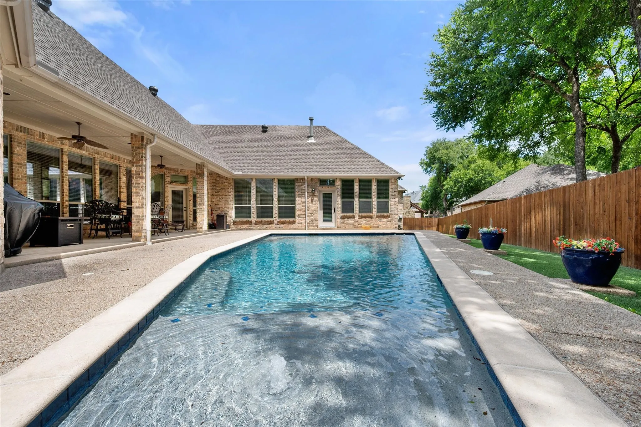 Rectangle swimming pool with a surrounding aggregate concrete patio