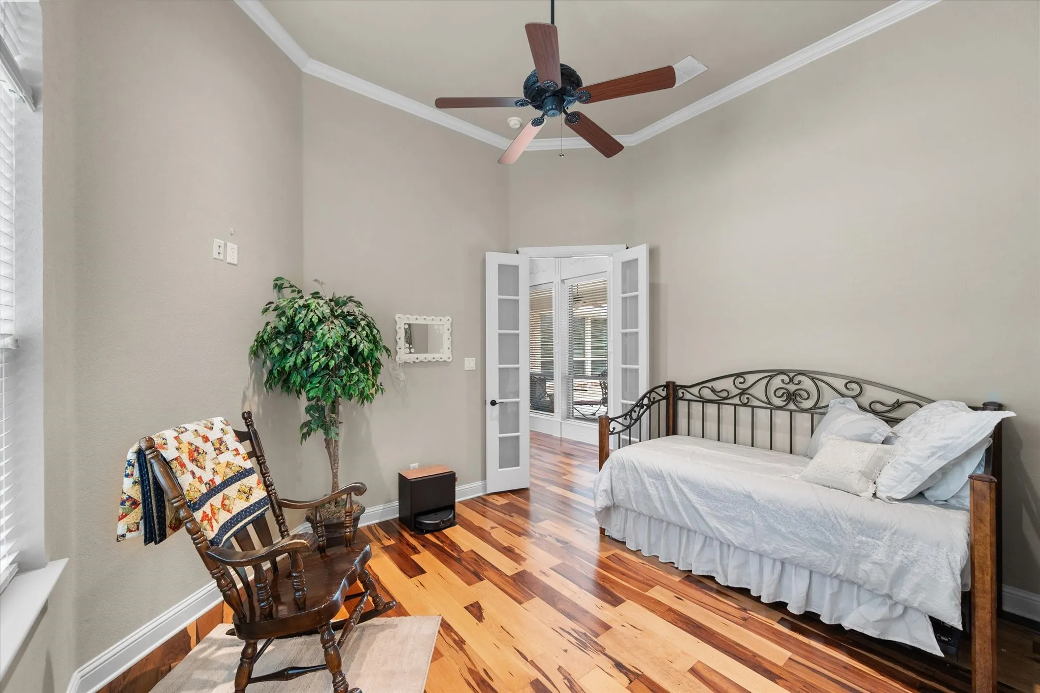 Room featuring wood-finish flooring, vaulted ceilings with crown molding, and a ceiling fan