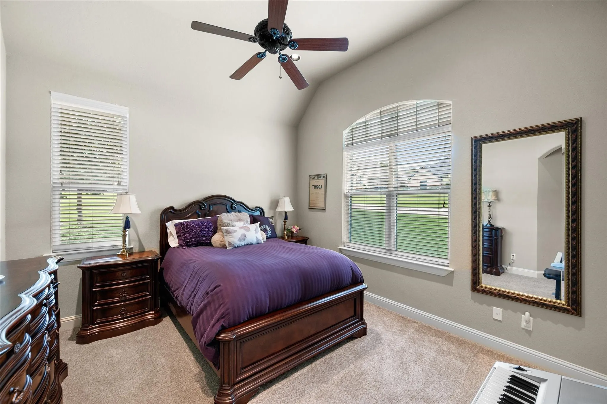 Vaulted ceilings featuring a ceiling fan, arched window, and plush carpet flooring