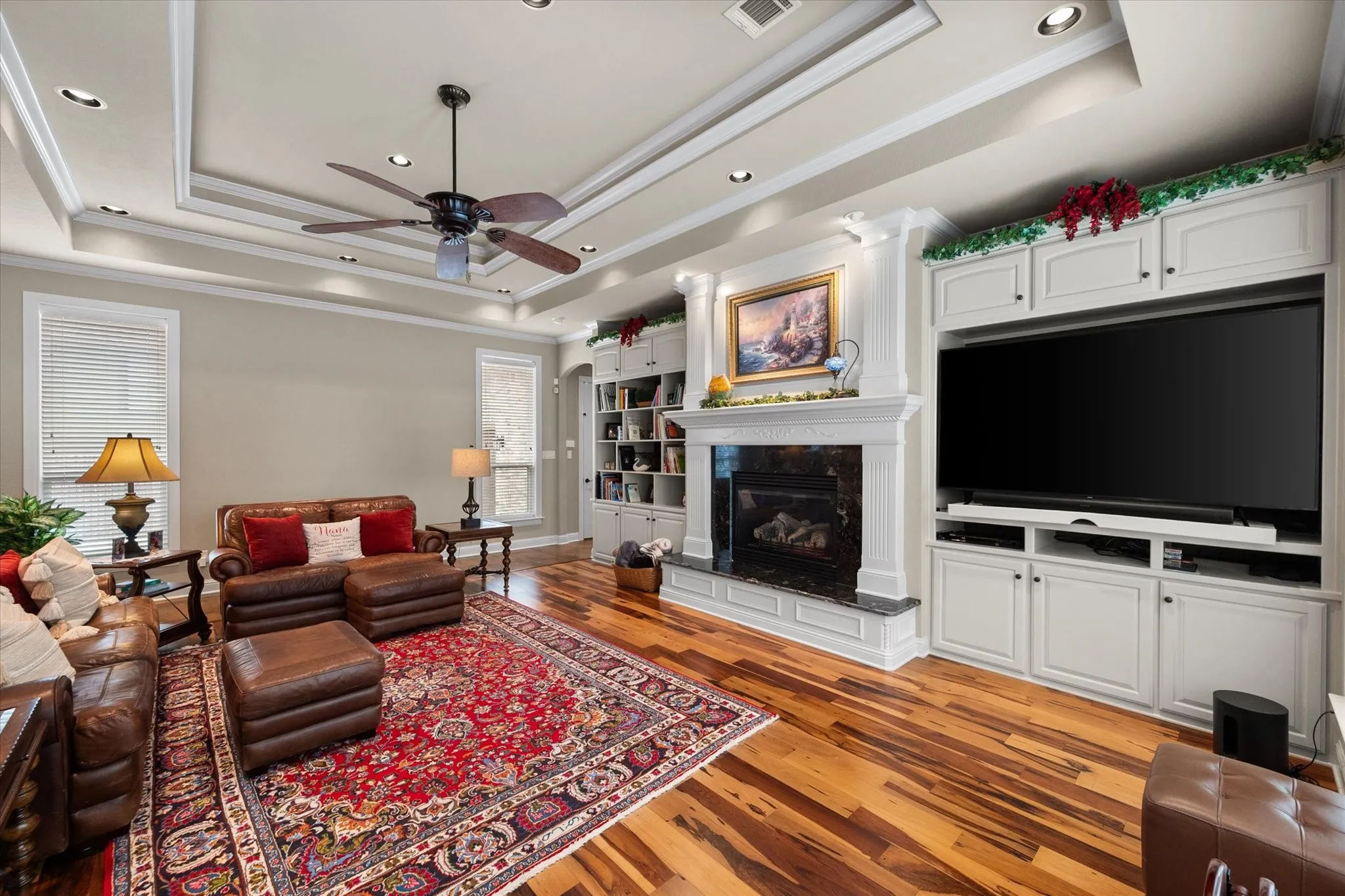 Spacious living area featuring wood-finish flooring and a tray ceiling with recessed lighting