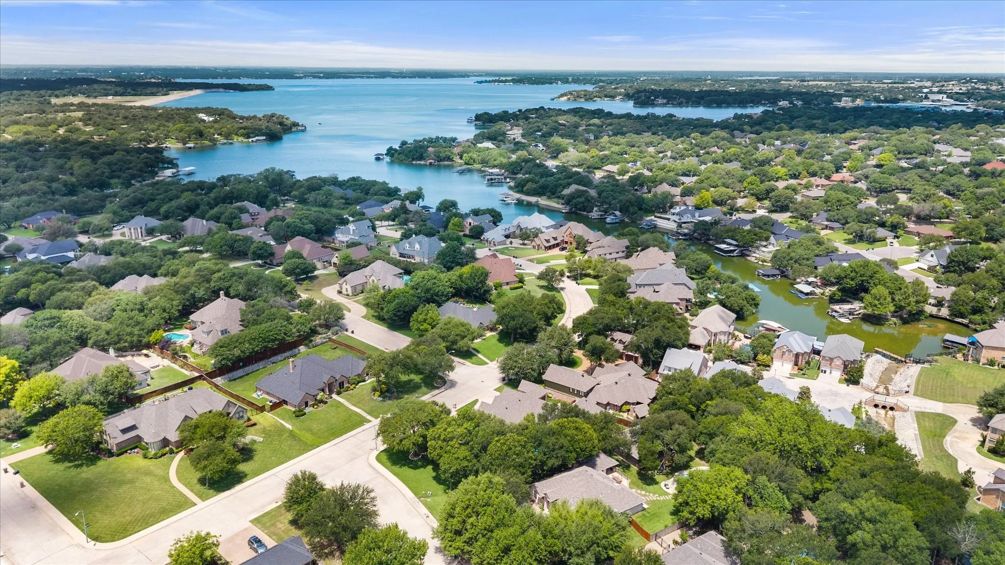 Aerial capture of a residential community featuring extensive tree coverage and waterfront properties