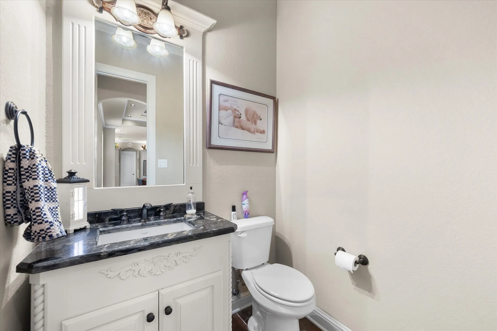 Bathroom vanity featuring a dark stone countertop, undermount sink, and a white cabinet with decorative accents