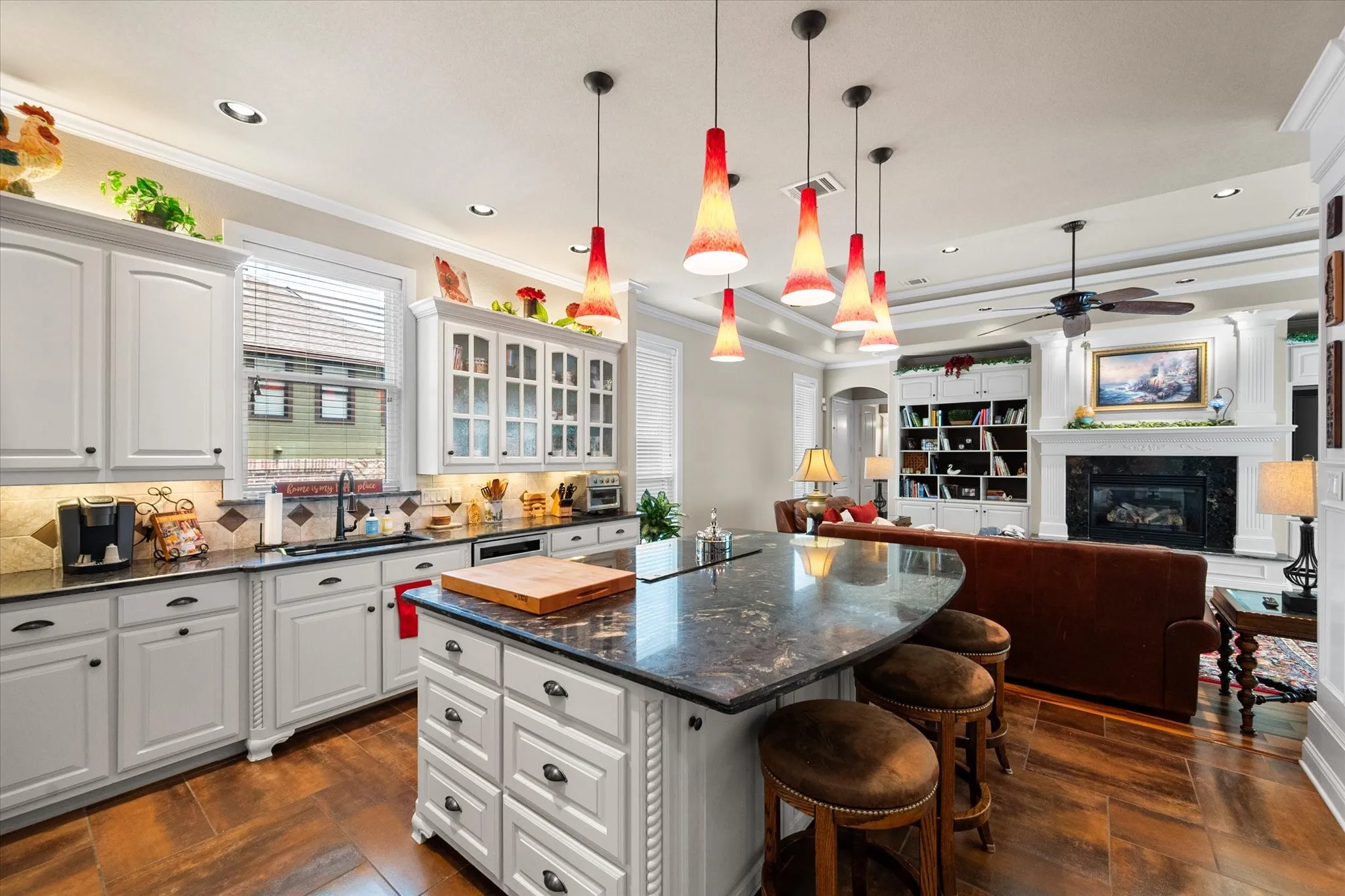Open-concept kitchen featuring white cabinetry, dark stone countertops, an island with seating, a tile backsplash, and wood-finish flooring
