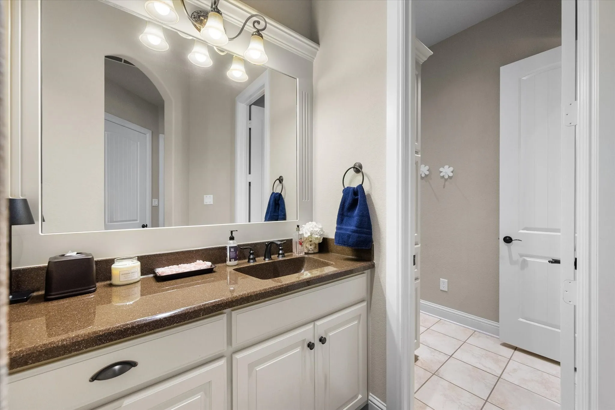 Bathroom vanity featuring a dark brown countertop, integrated sink, and white cabinetry with dark hardware