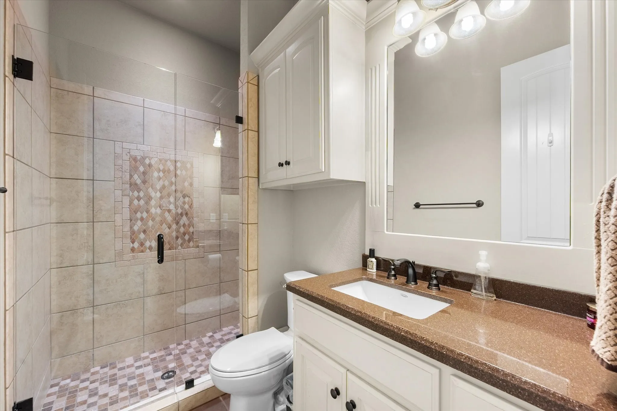 Walk-in shower with tiled walls and decorative mosaic accent
