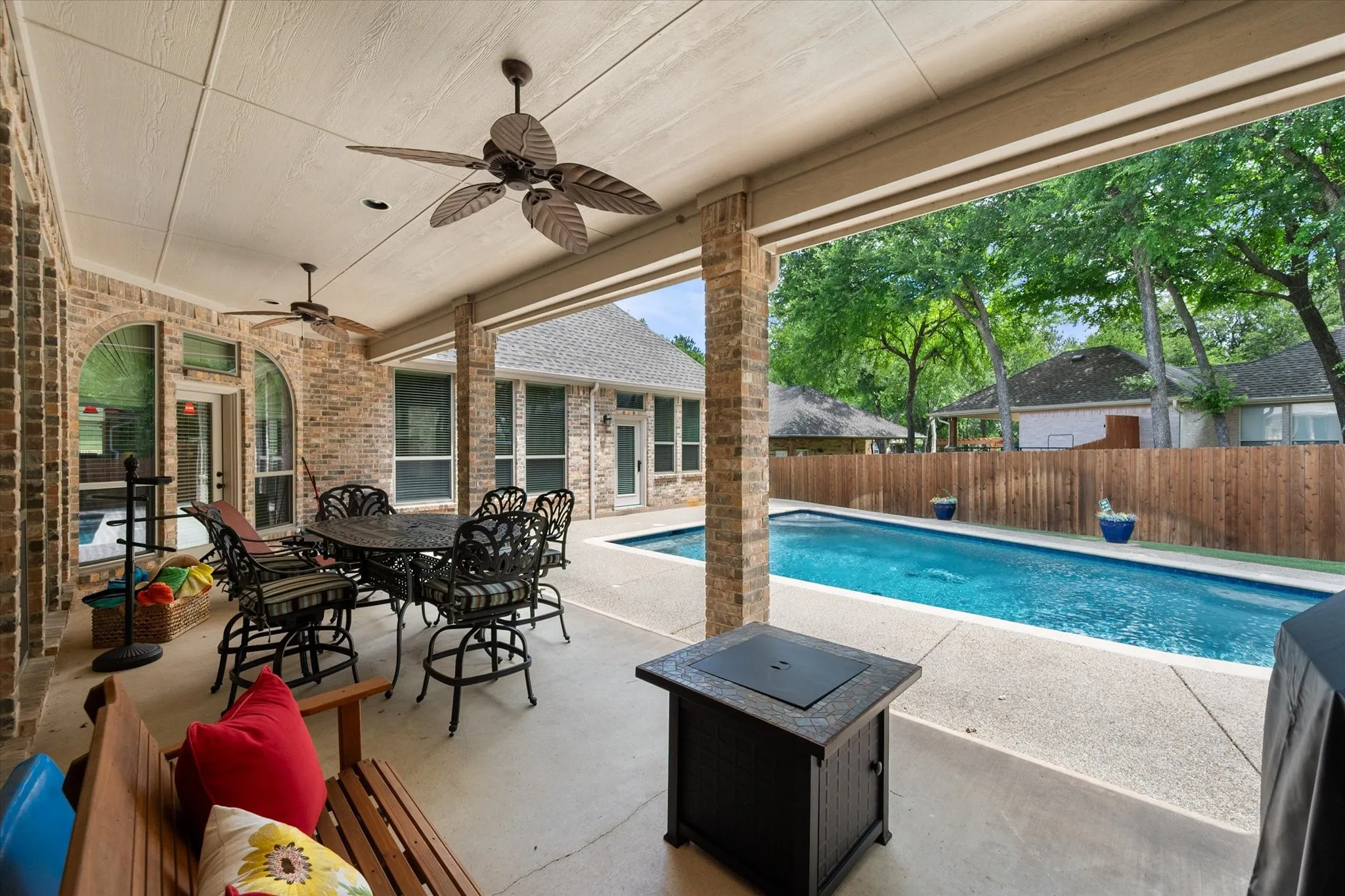 Covered patio featuring two ceiling fans, brick columns, and a concrete surface