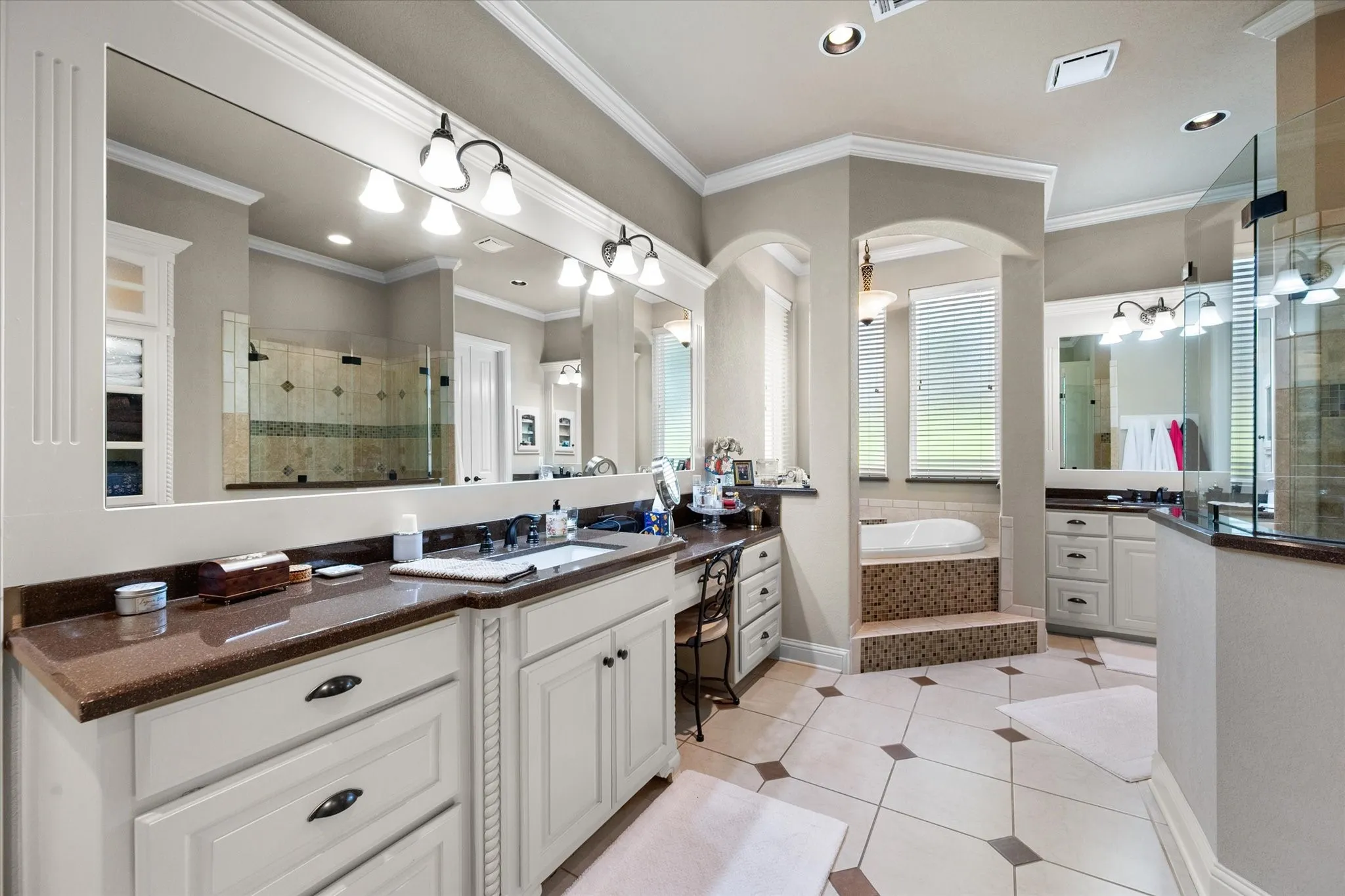 Spacious bathroom featuring expansive vanity countertops, a built-in makeup desk, and dual mirrors with sconce lighting