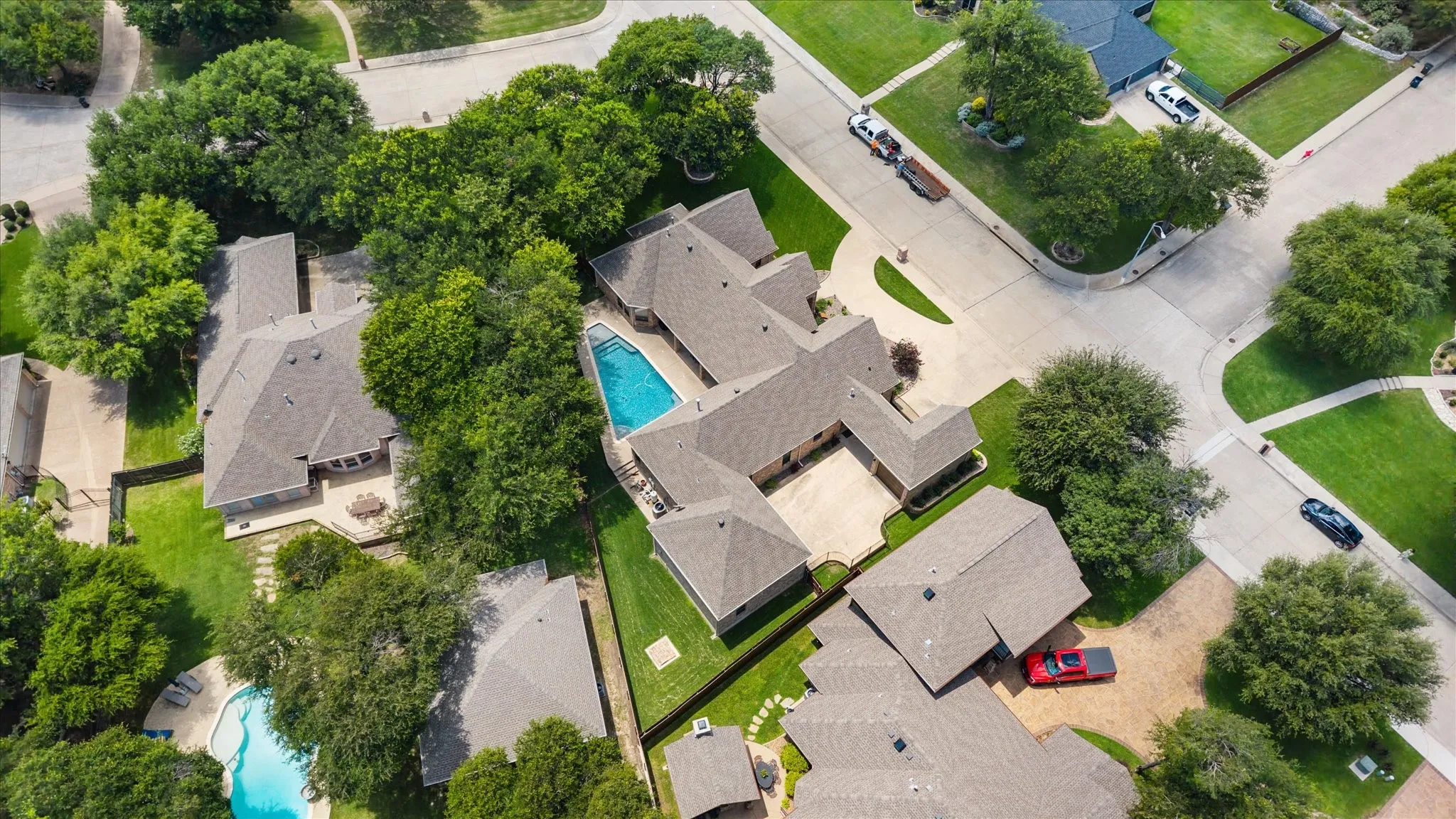 Aerial perspective showcasing multiple properties, including a residence with a swimming pool and extensive hardscaping