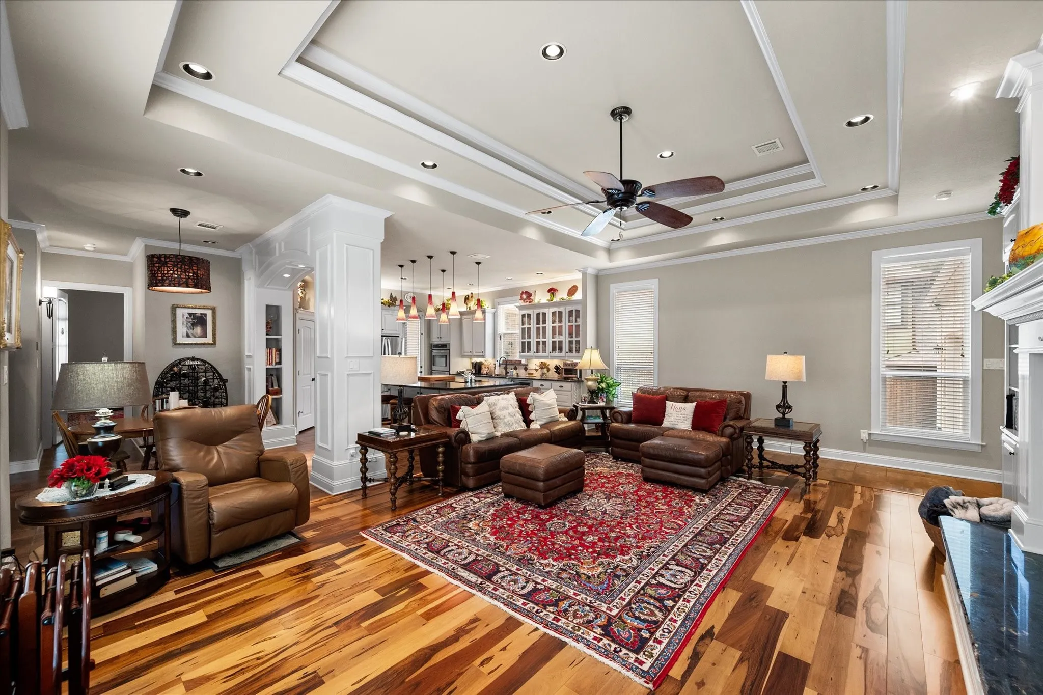 Living room featuring wood-finish flooring, a tray ceiling with recessed lighting, and a ceiling fan