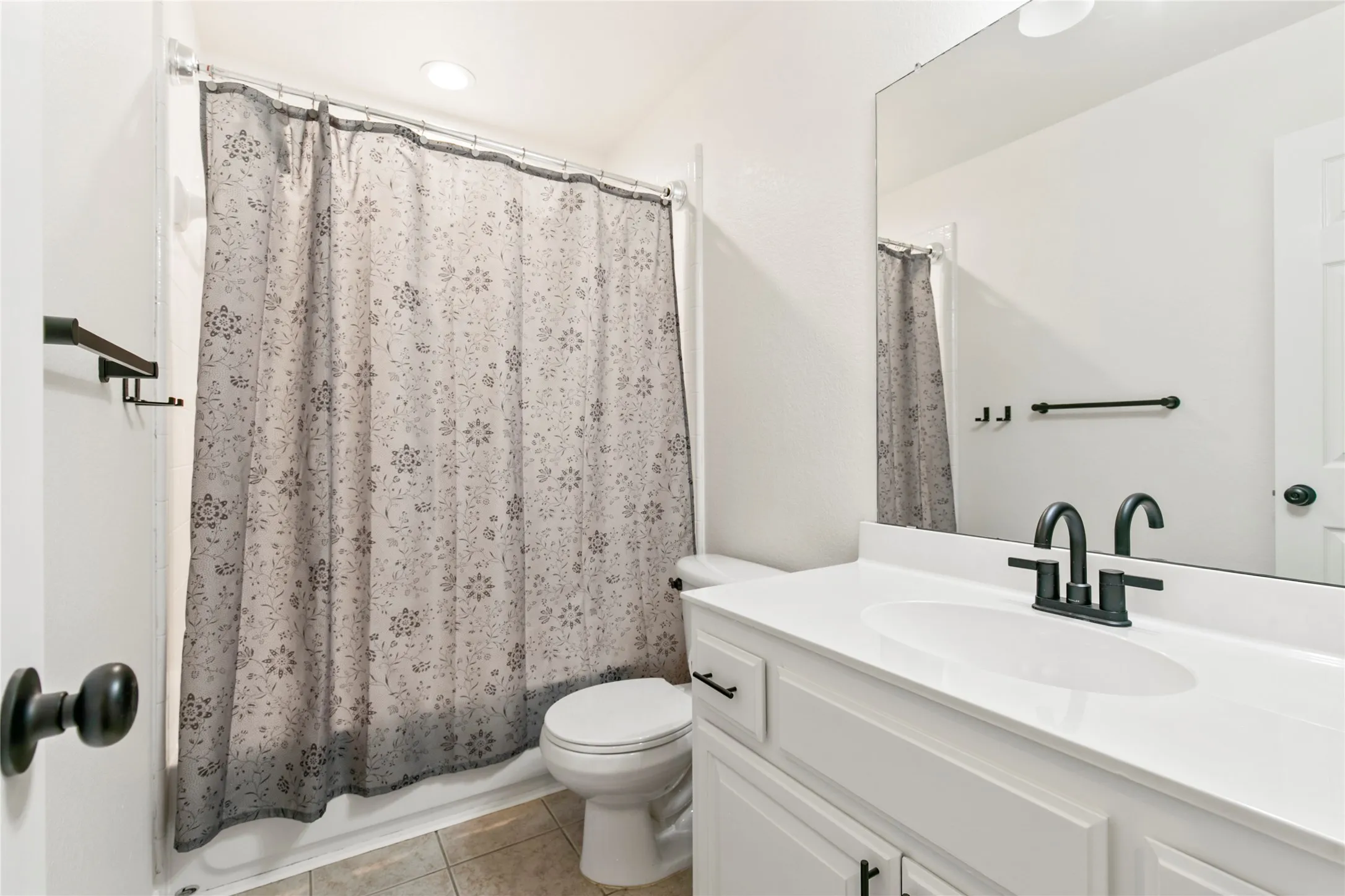 Bathroom vanity featuring a white countertop with an integrated sink and matte black faucet