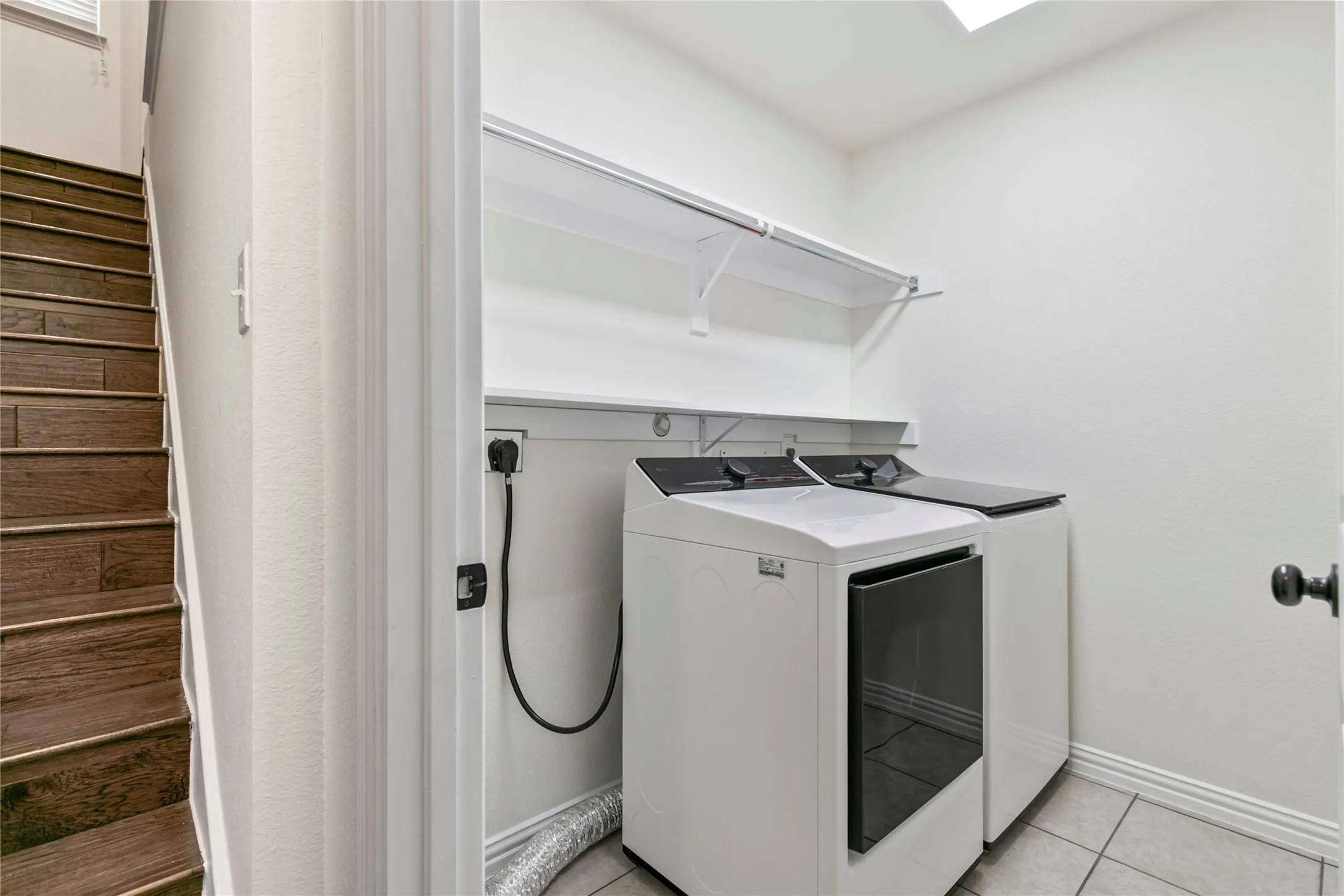 Dedicated laundry area featuring tile flooring, white walls, and built-in shelving