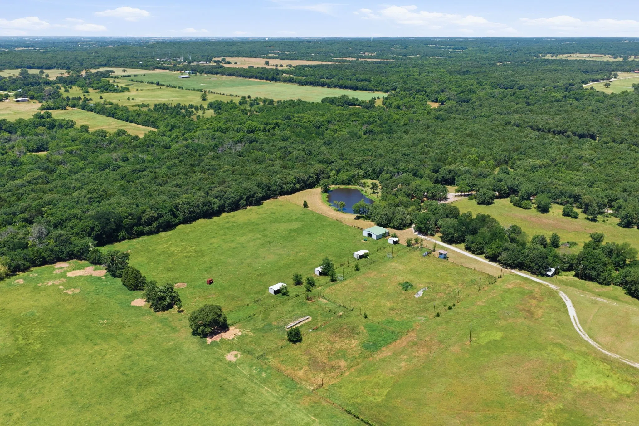 Lots of trees surrounding the arena , barn and loafing sheds.