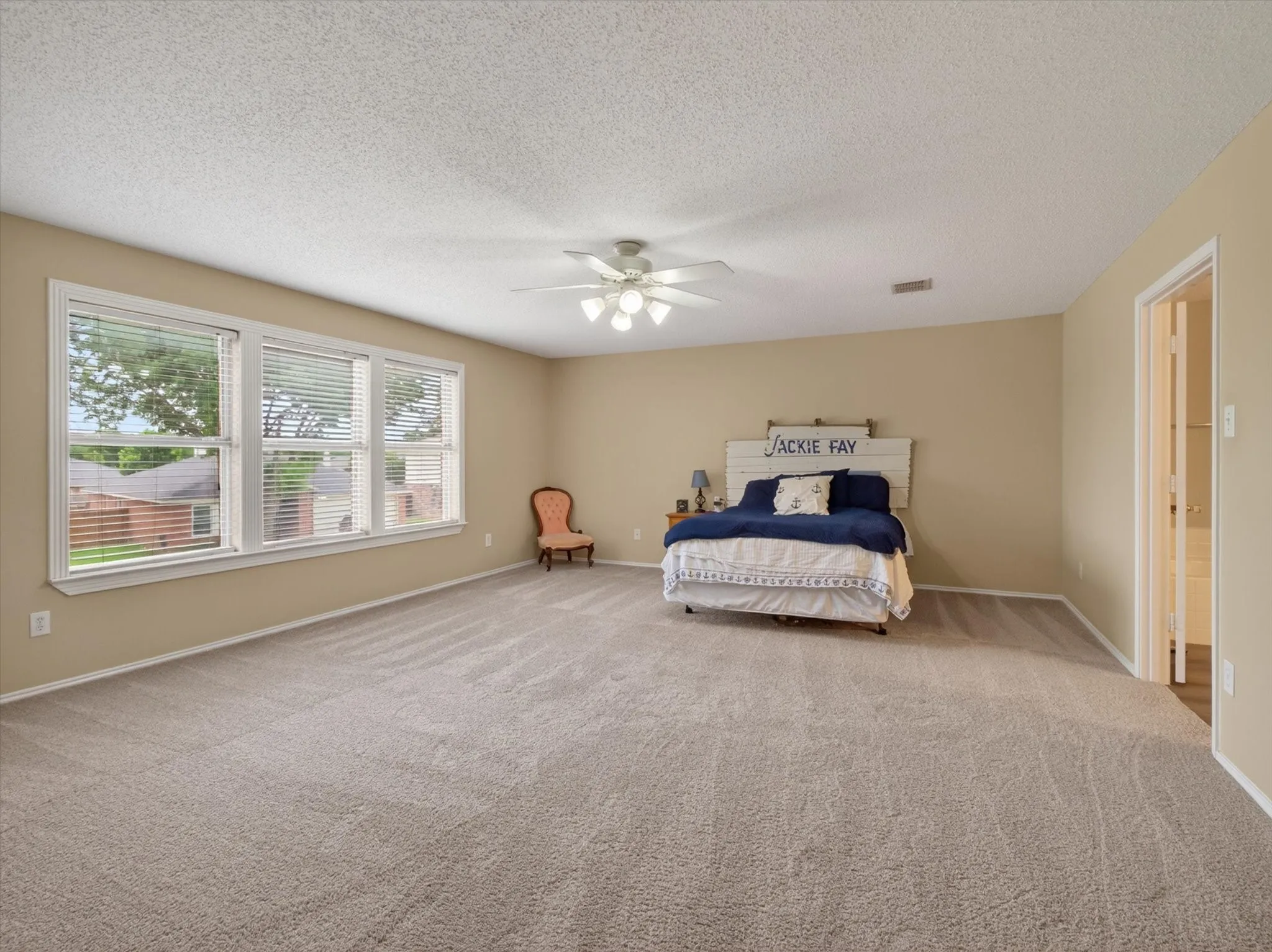 Spacious room featuring neutral carpeting, light-toned walls, and a ceiling fan