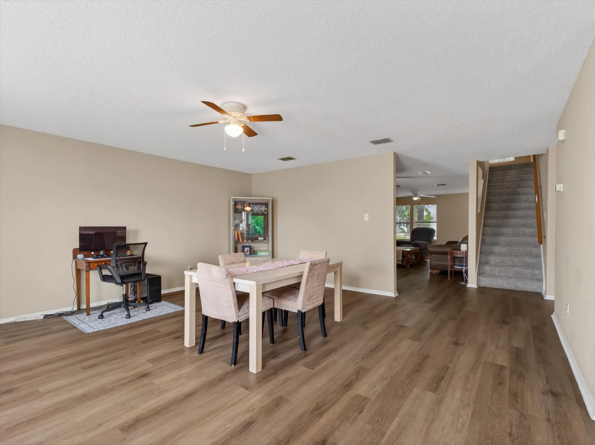 Open-concept living area featuring wood-finish flooring, neutral wall tones, and a ceiling fan with light fixture