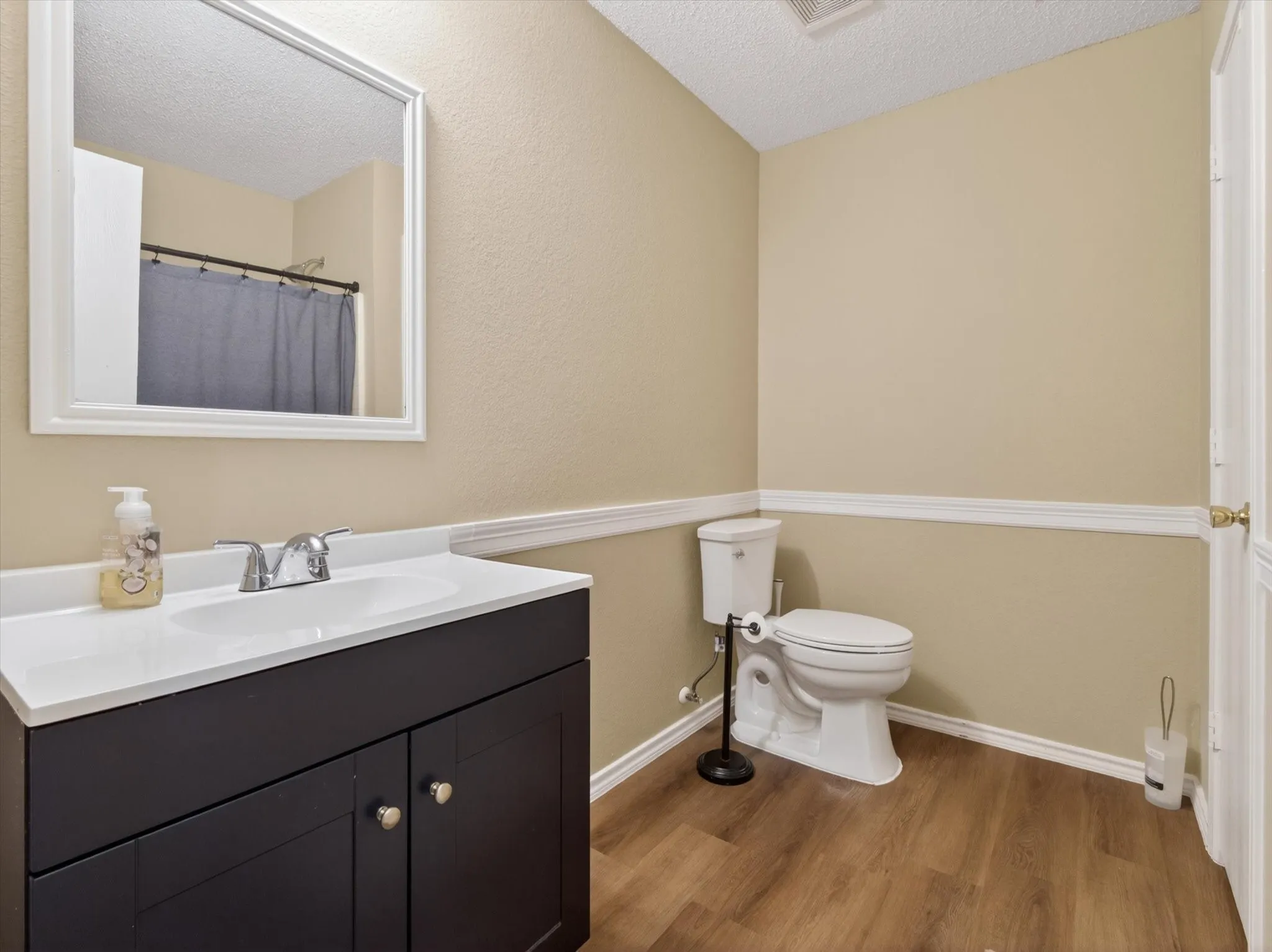 Bathroom featuring a dark wood-finish vanity with an integrated white sink, chrome faucet, and a framed wall mirror